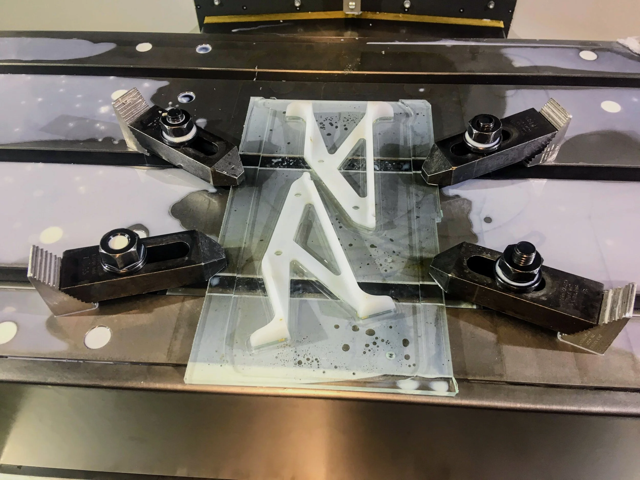 CNC machining the pattern out of UHMW. Fixturing accomplished with brass screws holding the stock to an acrylic plate.