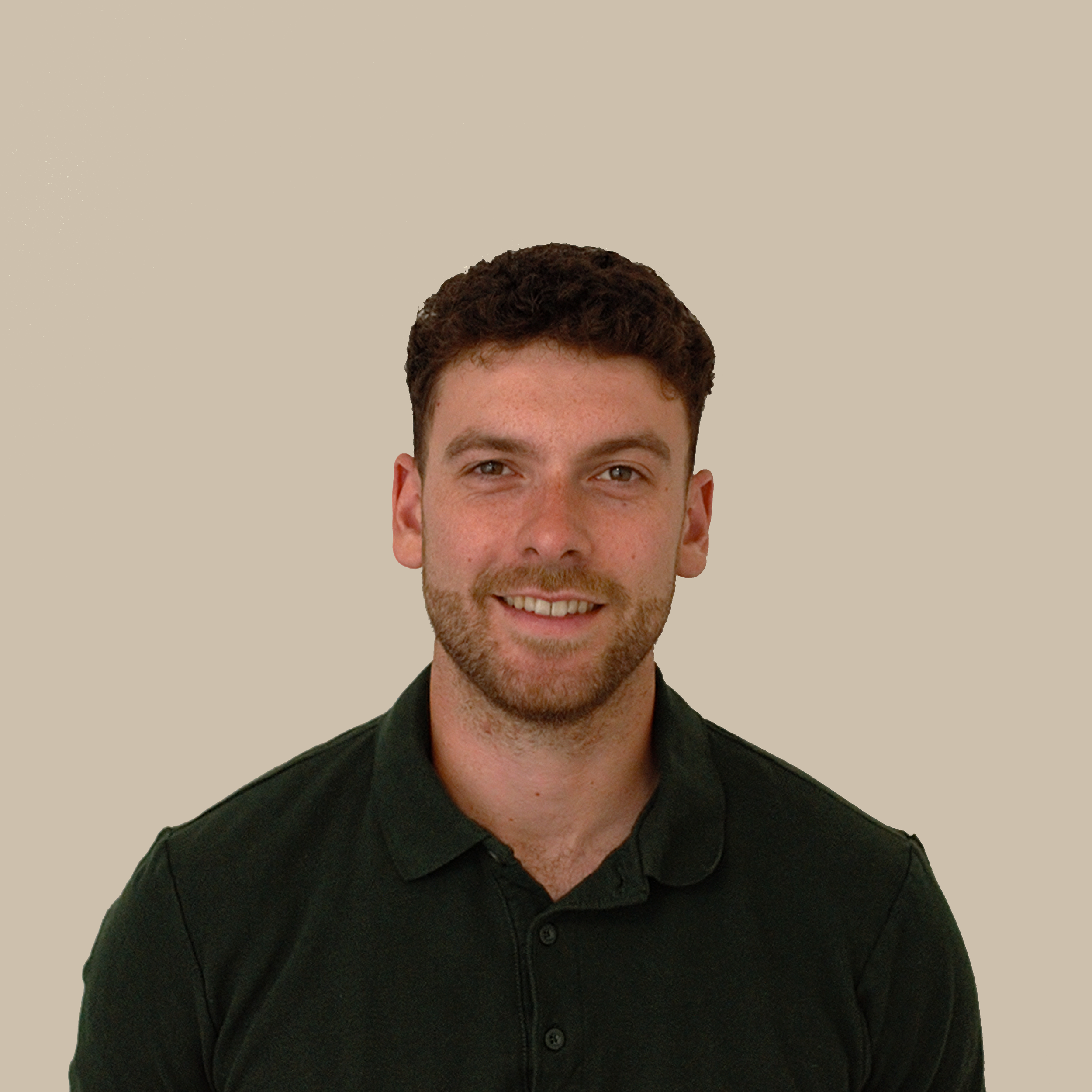 Close-up of a young man with short, curly dark hair, smiling and wearing a black collared shirt against a beige background.
