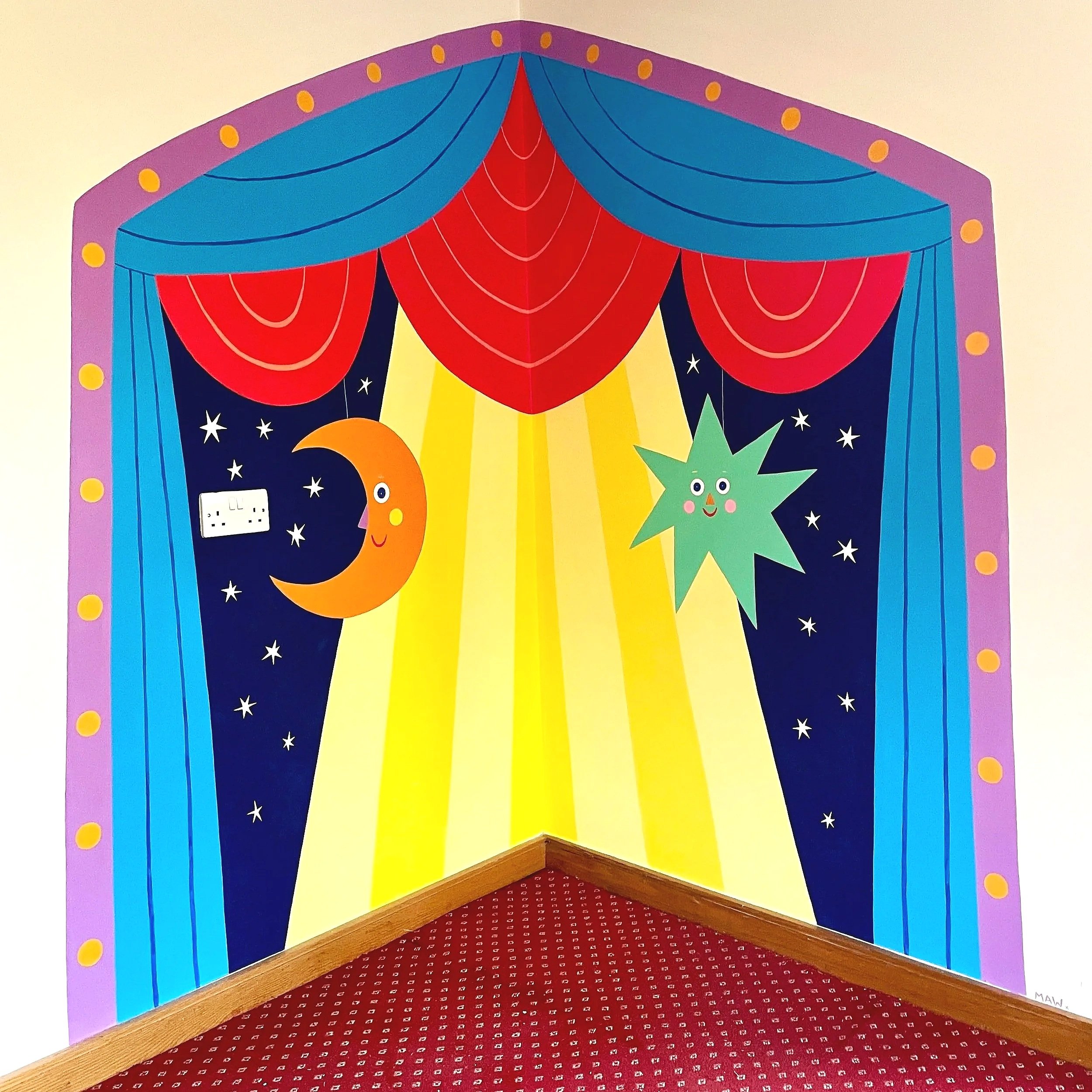A vibrant, hand-painted mural of a theatrical stage with red curtains and celestial-themed decorative elements in a children’s hospice playroom, by Melanie Williamson