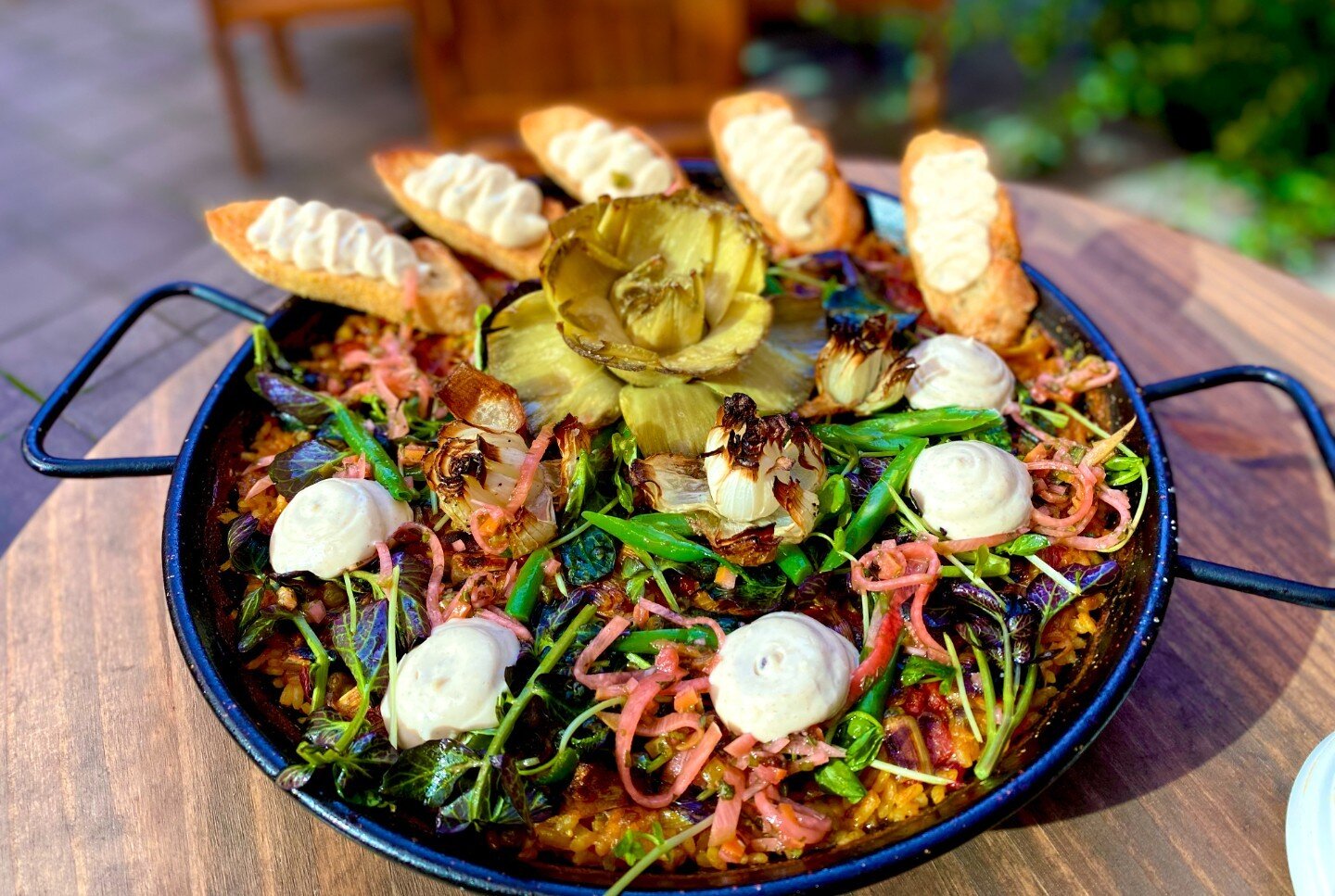 In honor of National Paella Day we are celebrating with a Spring Vegetable Paella. Charred onion and leek stock with turmeric. Bomba rice, braised leeks, peas, piquillo peppers, spring onion. Garnish - confit whole artichoke, spring onion flowers, re