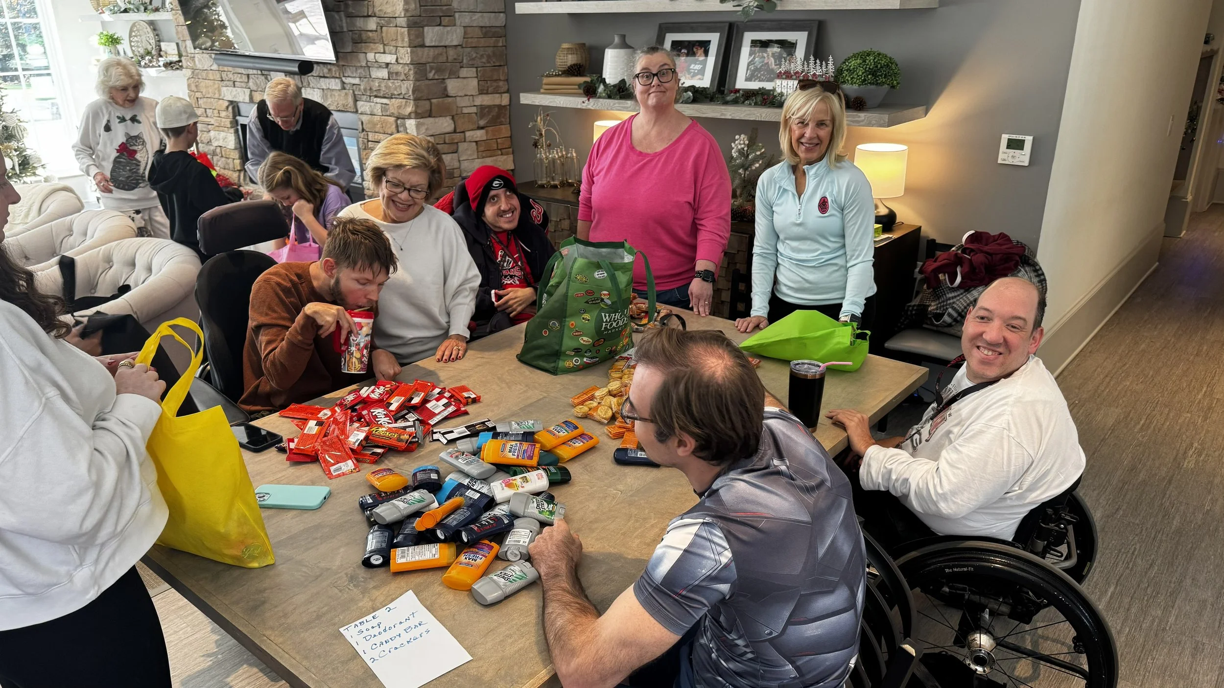 Champions Place residents: Derek, Josh, Corey, Adam gathered around the table preparing the bags. Volunteers from Mt. Pisgah and caregivers from Champions Place also pictured.
