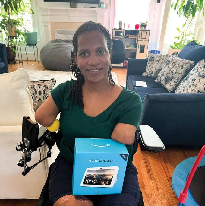 Champions Place@Home recipient, Carria Williams, smiling with some of her new technology from the CP@Home program.