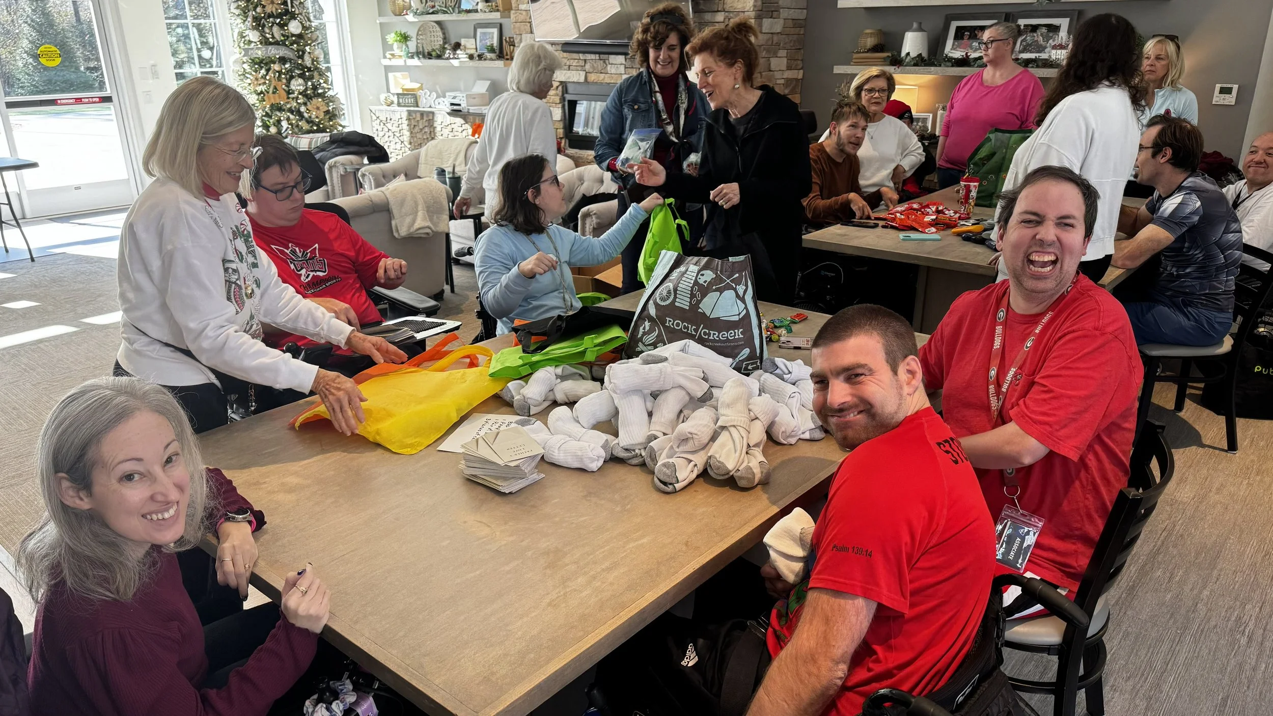 Champions Place residents: Ashley, Matt, Ryan, Noelle, and Tim sitting around the table preparing items to put into the bags.