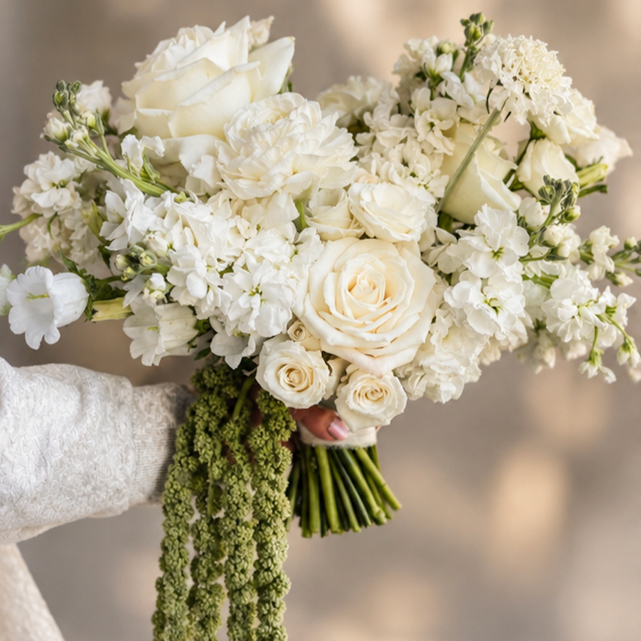 A fluffy white bridal bouquet with roses, stock, scabiosa, ranunculus and campanula