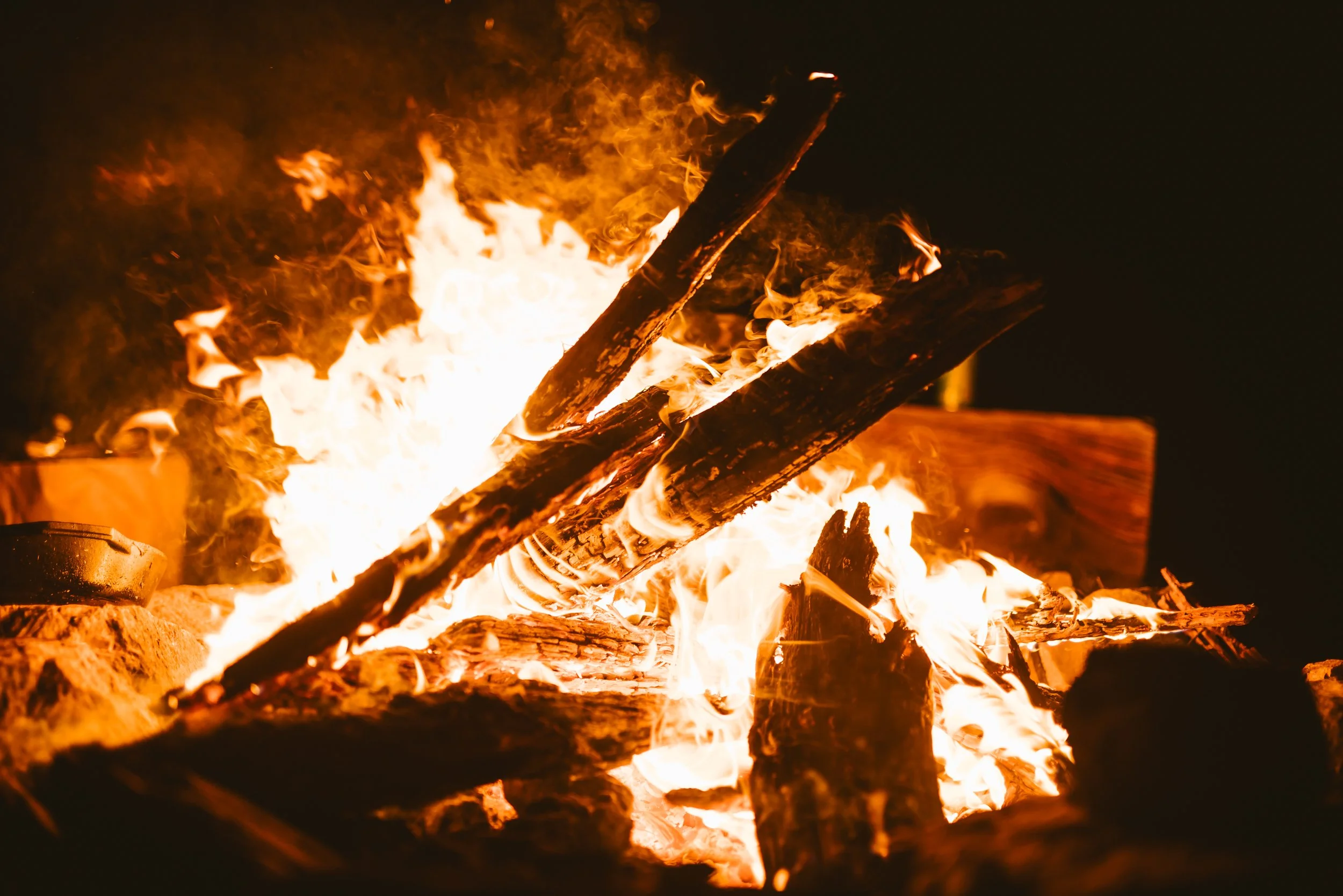 Campfire with burning wood logs and flames at night