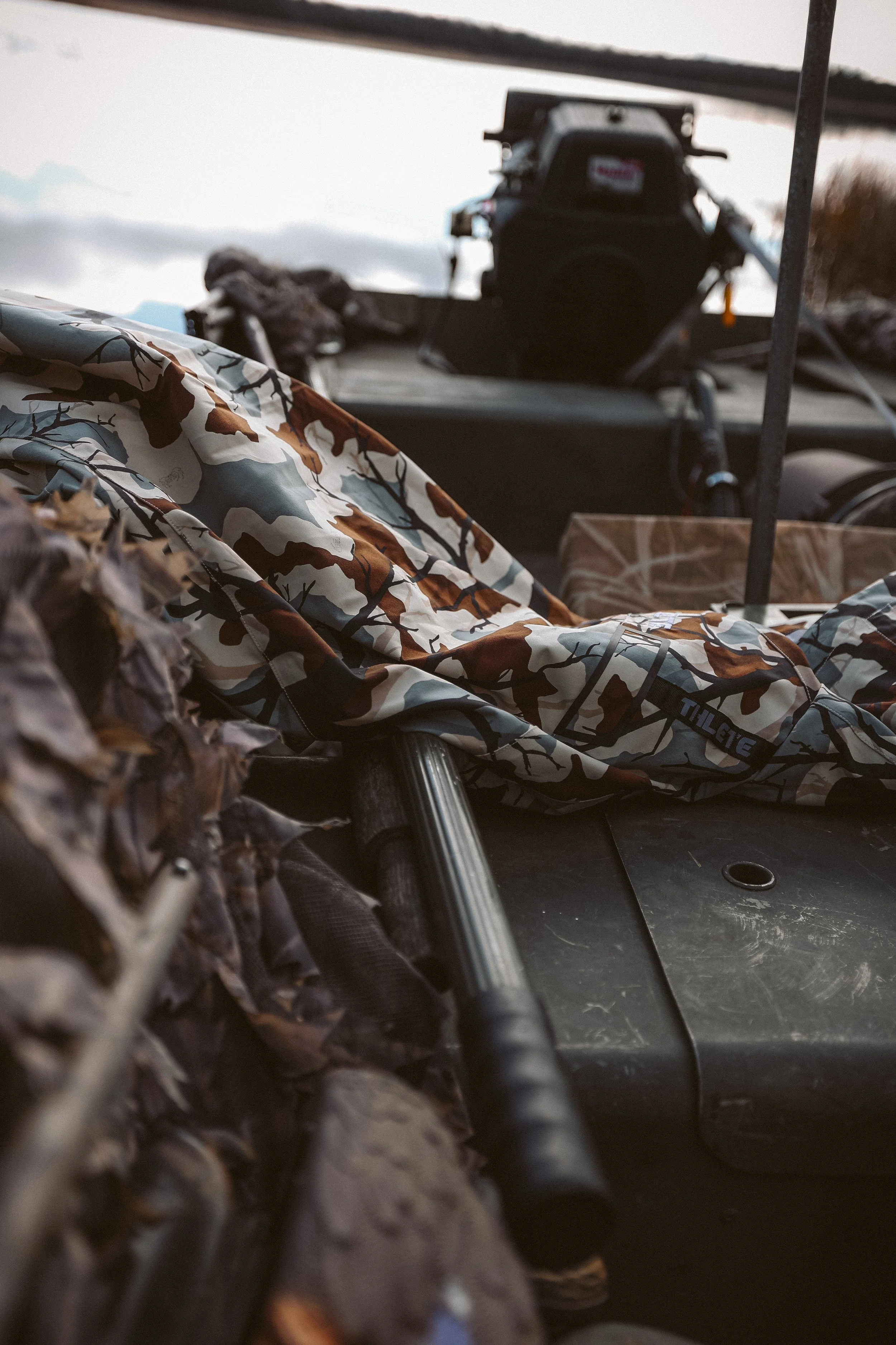 Camouflage material and a black handle resting on a flat surface with a motor in the background.