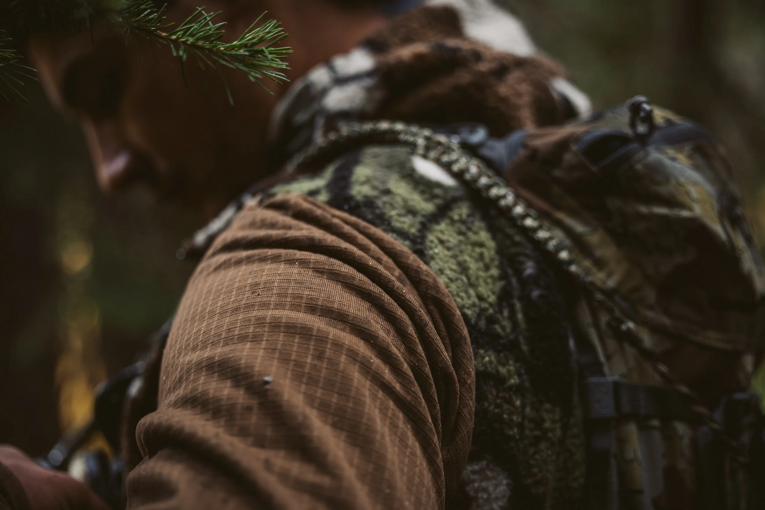 Person in brown jacket and camo backpack in forest