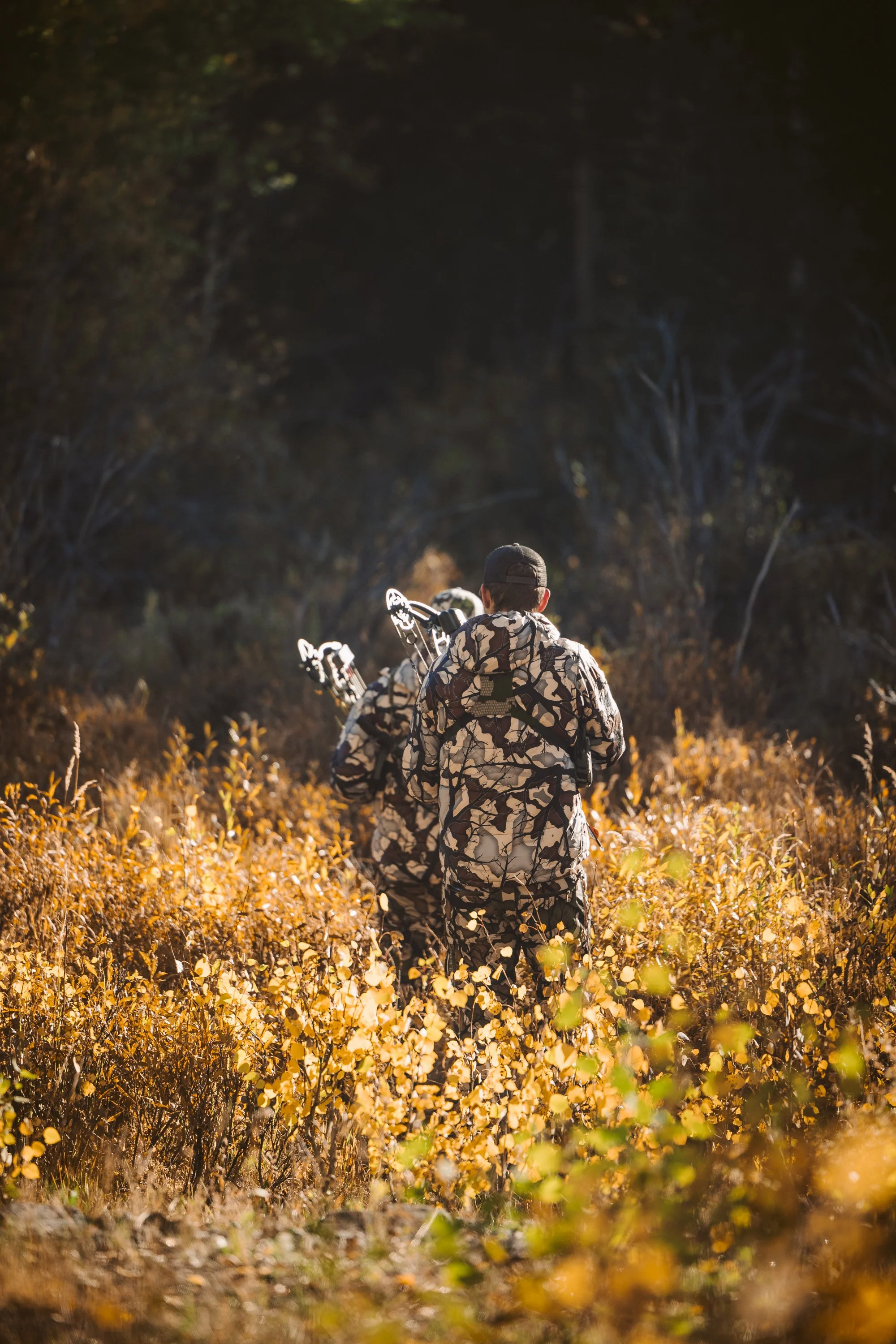 Hunters in camouflage walking through autumn forest