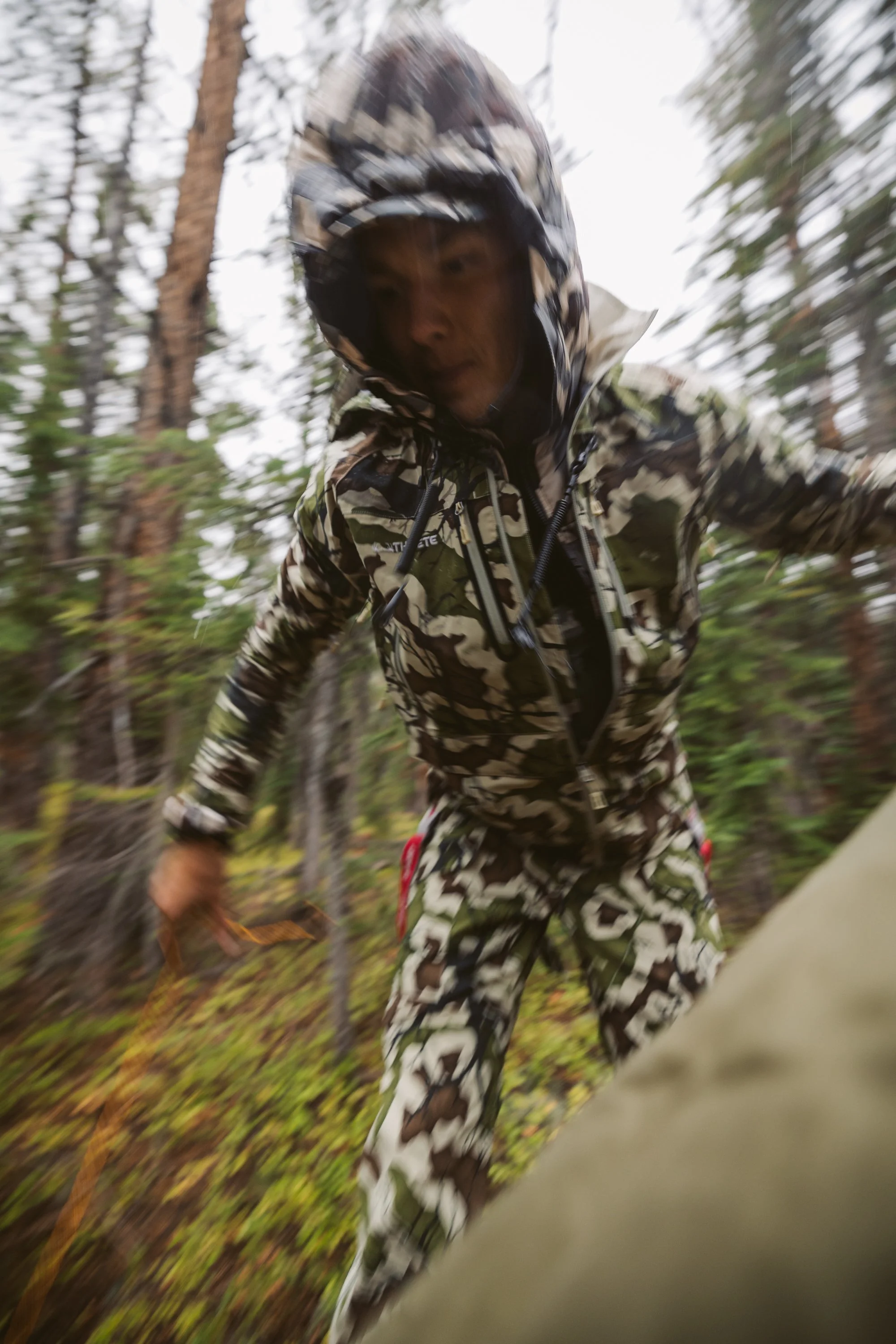 Person in camo rain gear hiking in a forest