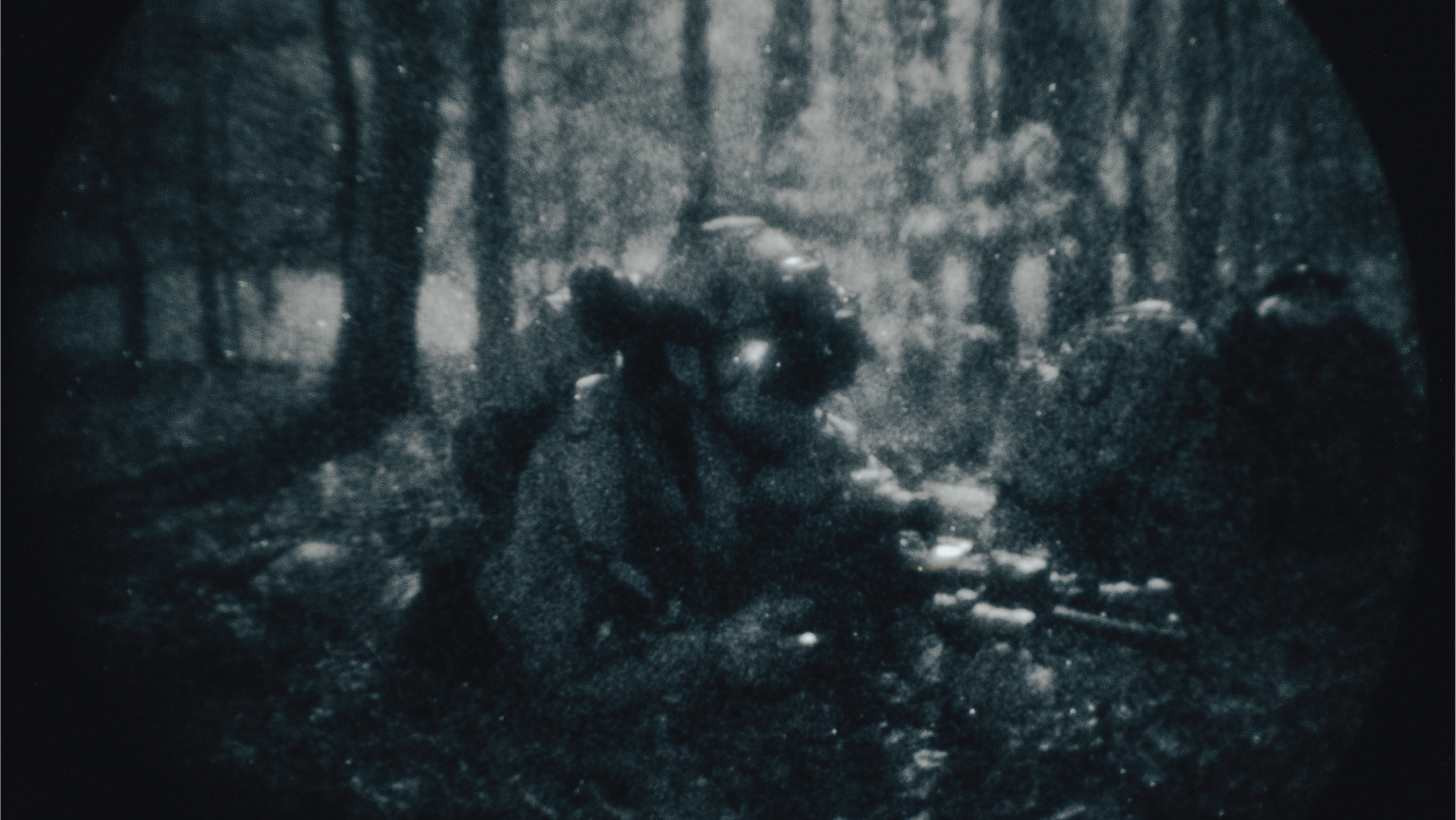 Night vision image of soldiers with rifles in a forest.