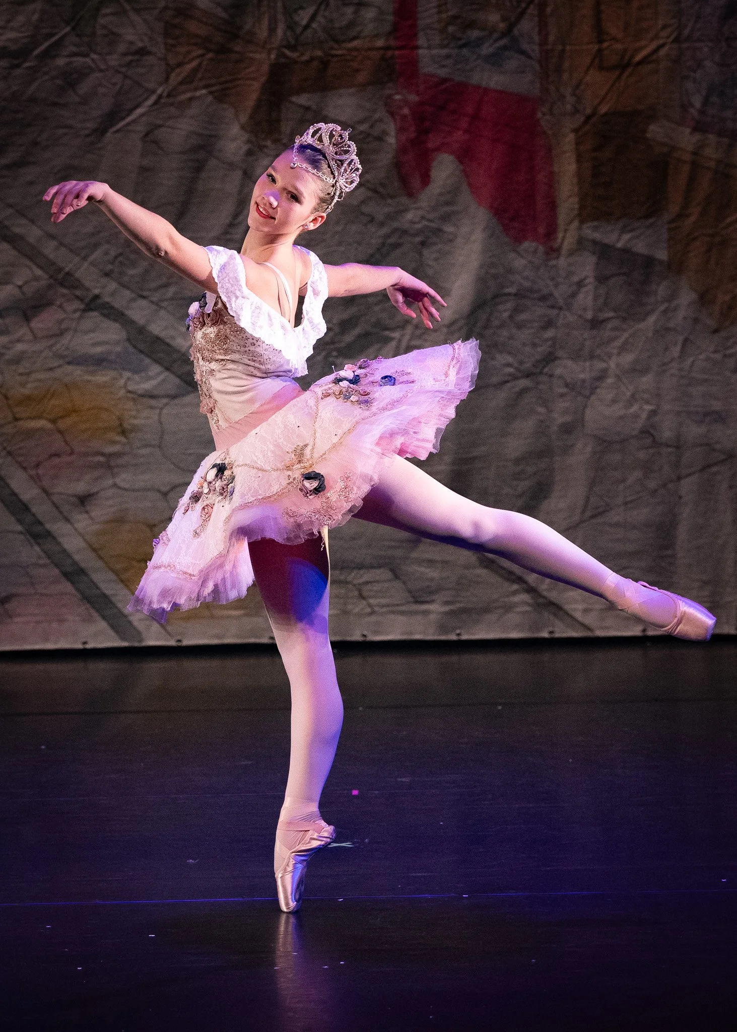 Two ballet dancers, a male and a female, performing a dance on stage. The female is wearing a pink tutu and the male is dressed in white and gold costume.