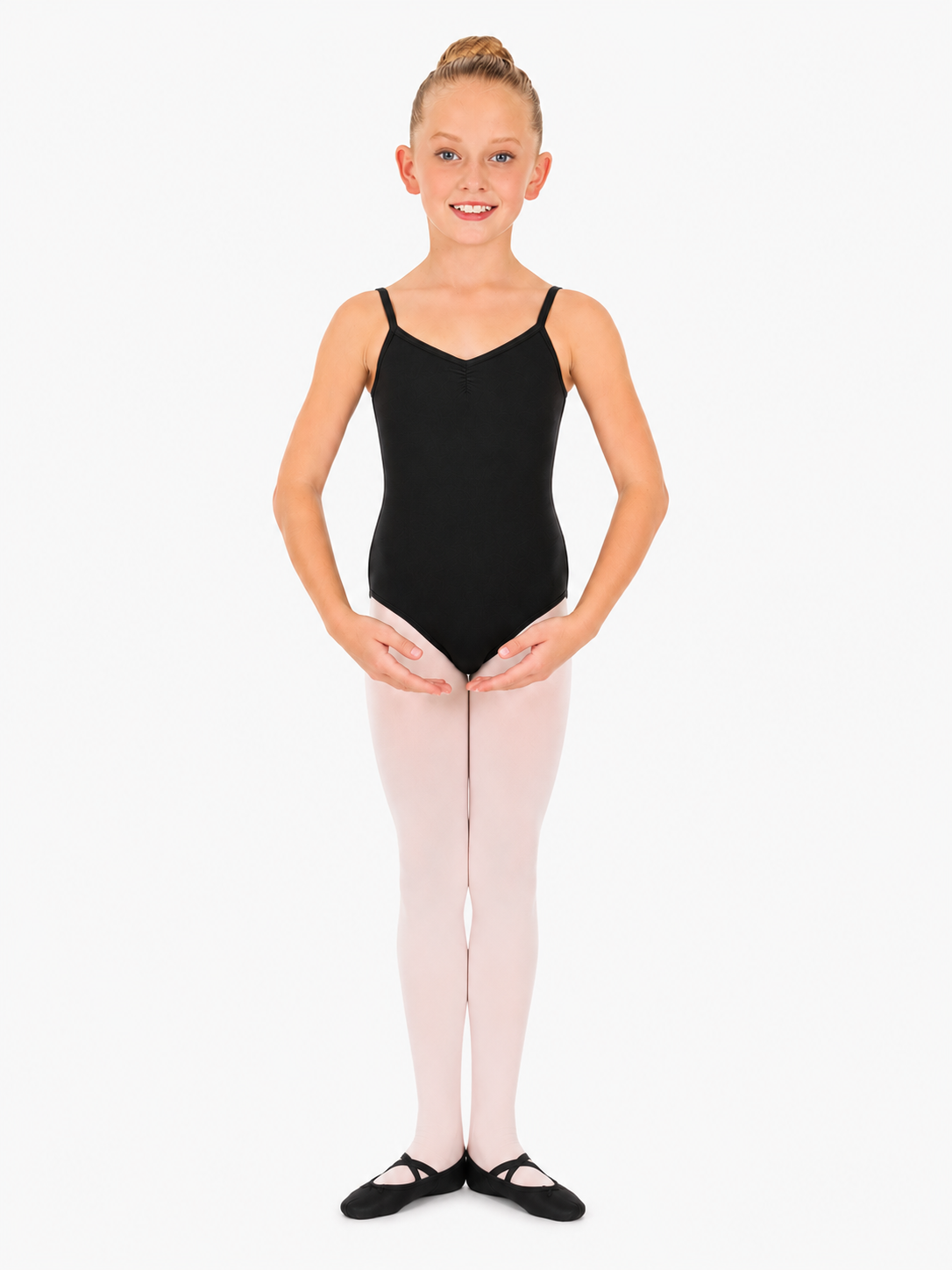A young girl with light brown hair in a bun, smiling, wearing a light green leotard with spaghetti straps and white tights.