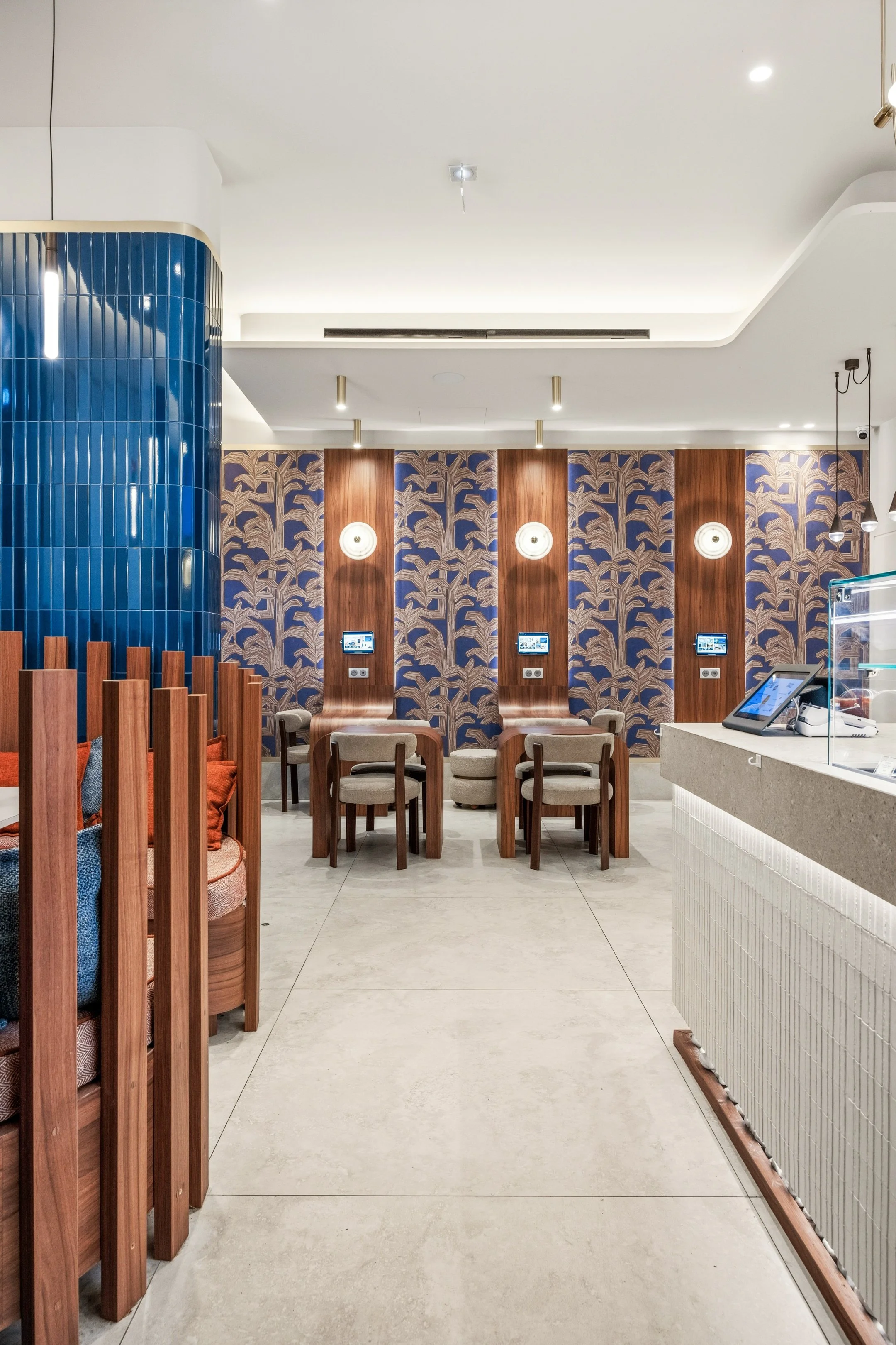 La lumière a été soigneusement étudiée, tout comme les plafonds, afin de structurer l’espace et créer différentes ambiances. Îlot central, tables individuelles, bar et petit salon coexistent harmonieusement dans cet espace restreint, chaque zone béné