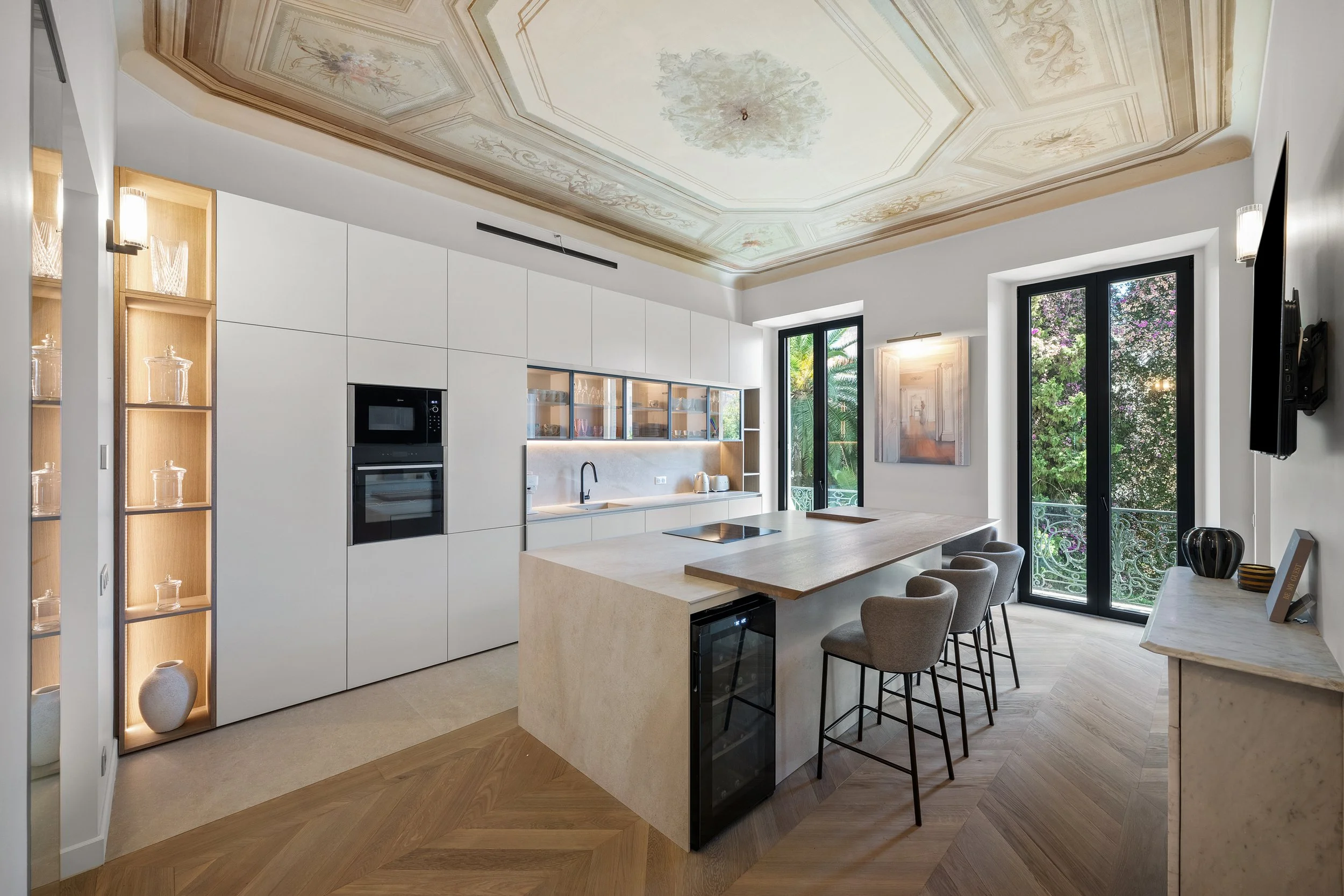 Conçue comme un lieu central de convivialité, la cuisine et la salle à manger intègrent un îlot carrelé en grandes plaques de @neolithofficial, surmonté d’un plateau biseauté en chêne massif. L’îlot regroupe l’ensemble des rangements et des électromé