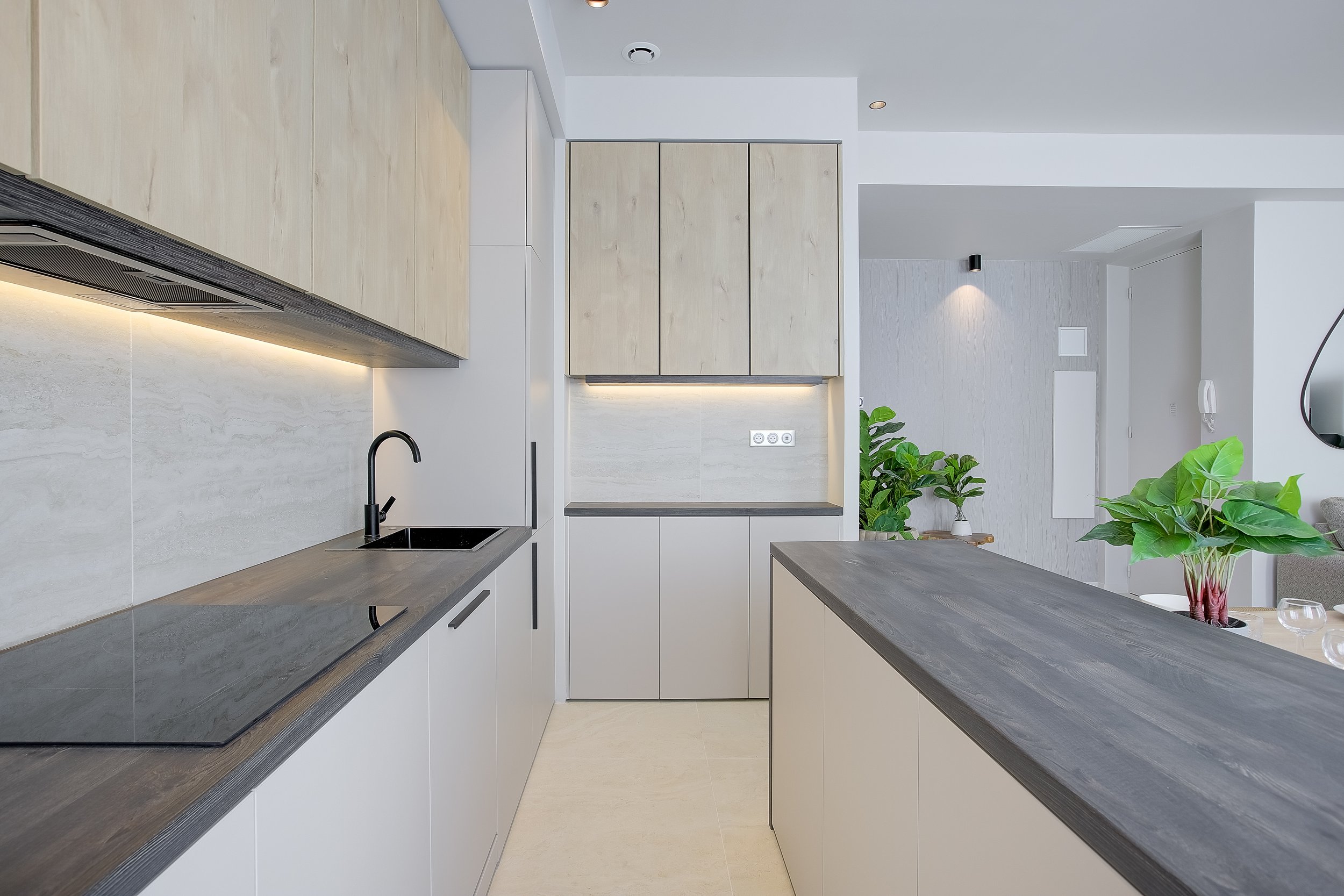 Building Ideas a créé pour GINA une cuisine sur mesure, avec notamment un îlot central élégant par sa bordure en bois exotique, ajoutant une touche de chaleur au meuble laqué taupe clair. Le mobilier de cuisine et les placards ont été spécialement co