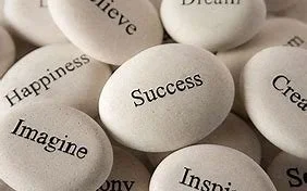 Smooth white stones engraved with positive words like 'Success' and 'Happiness'