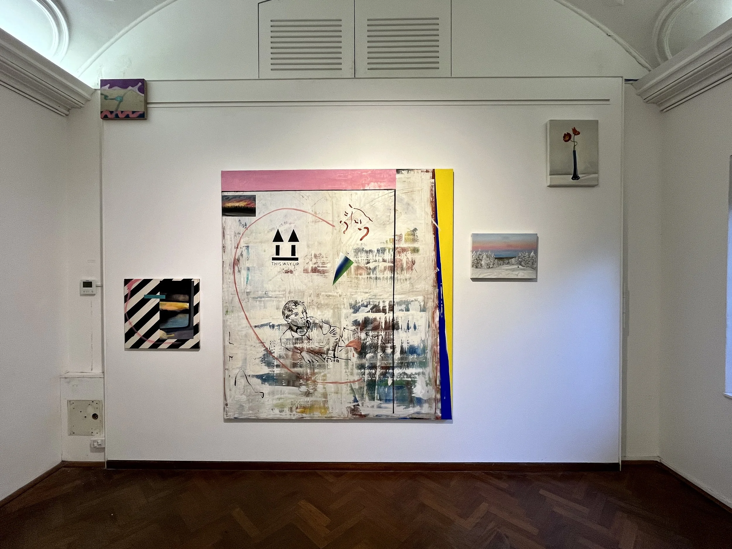 Art gallery with large abstract painting featuring a mix of colors, lines, and shapes, with smaller framed artworks around it on white walls.