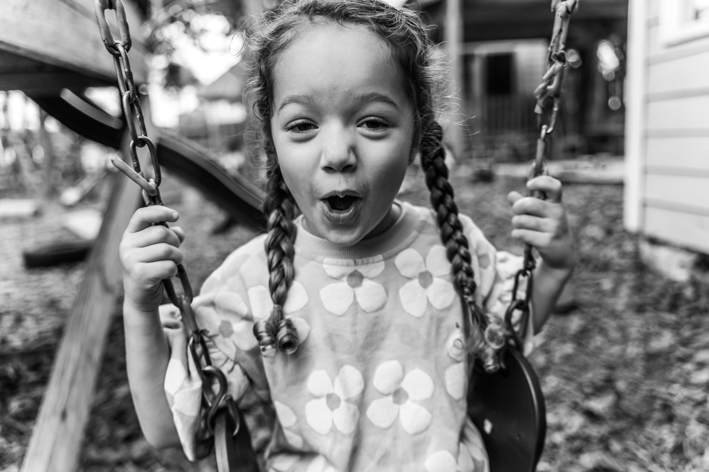 Young girl making a funny face, sticking out her tongue and holding up a peace sign with her hand, in an outdoor setting.