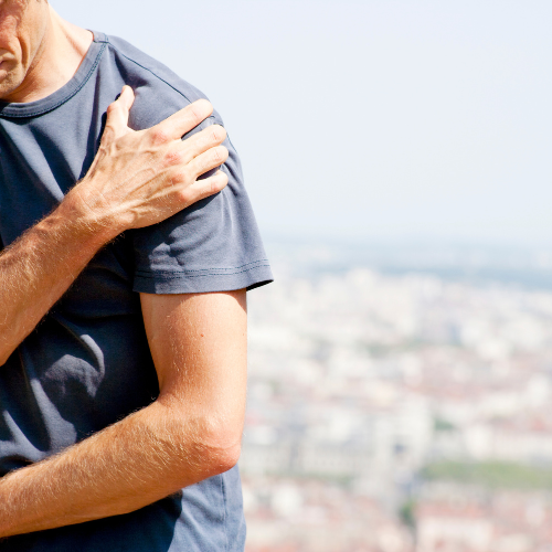 A man clutching his shoulder with his hand, indicating pain or discomfort.