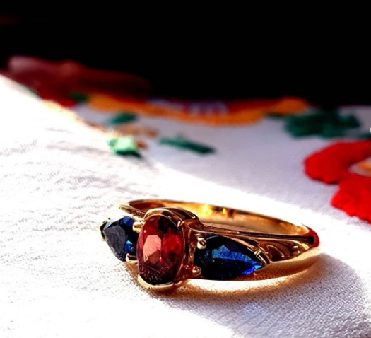 Vintage+9ct+Golden+ring+with+a+Sparkling+Garnet,+hugged+by+Sapphires.png
