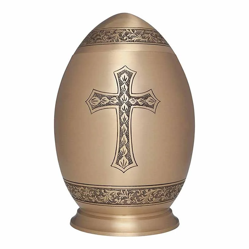 Brass cremation urn shaped like an egg with a cross engraving
