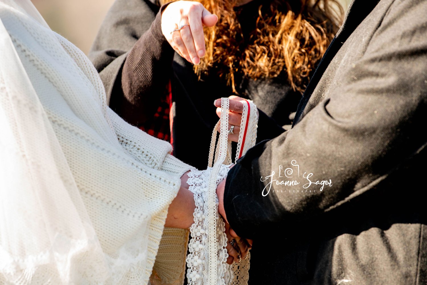 Bride and grooms hands are joined in a hand fasting during wedding