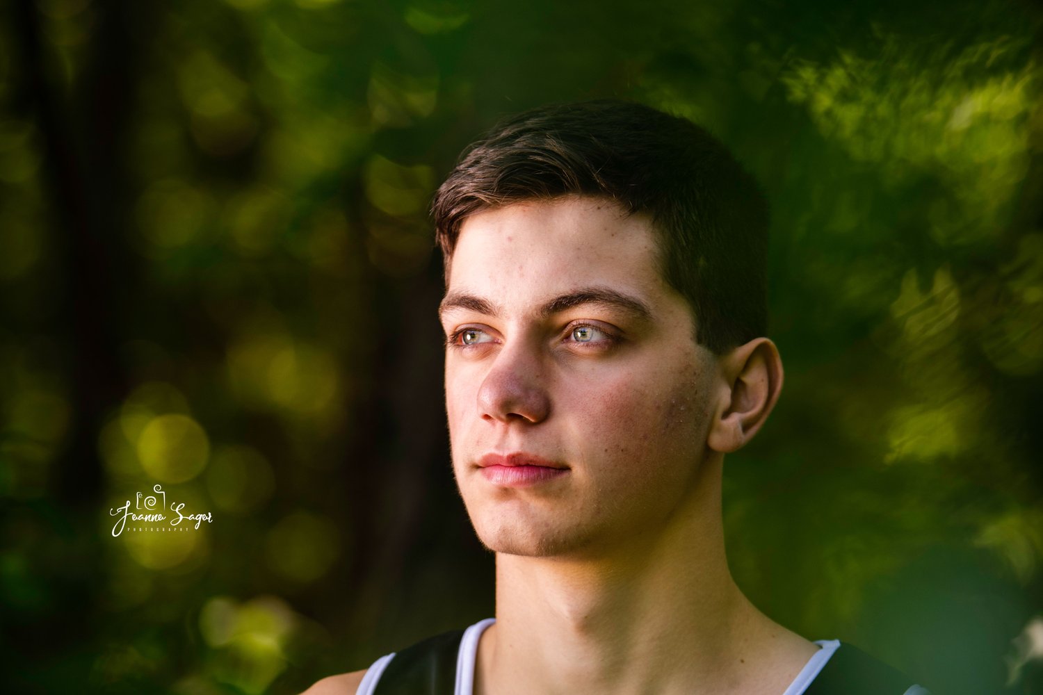 a portrait of a teenage boy up close against a backdrop of greenery