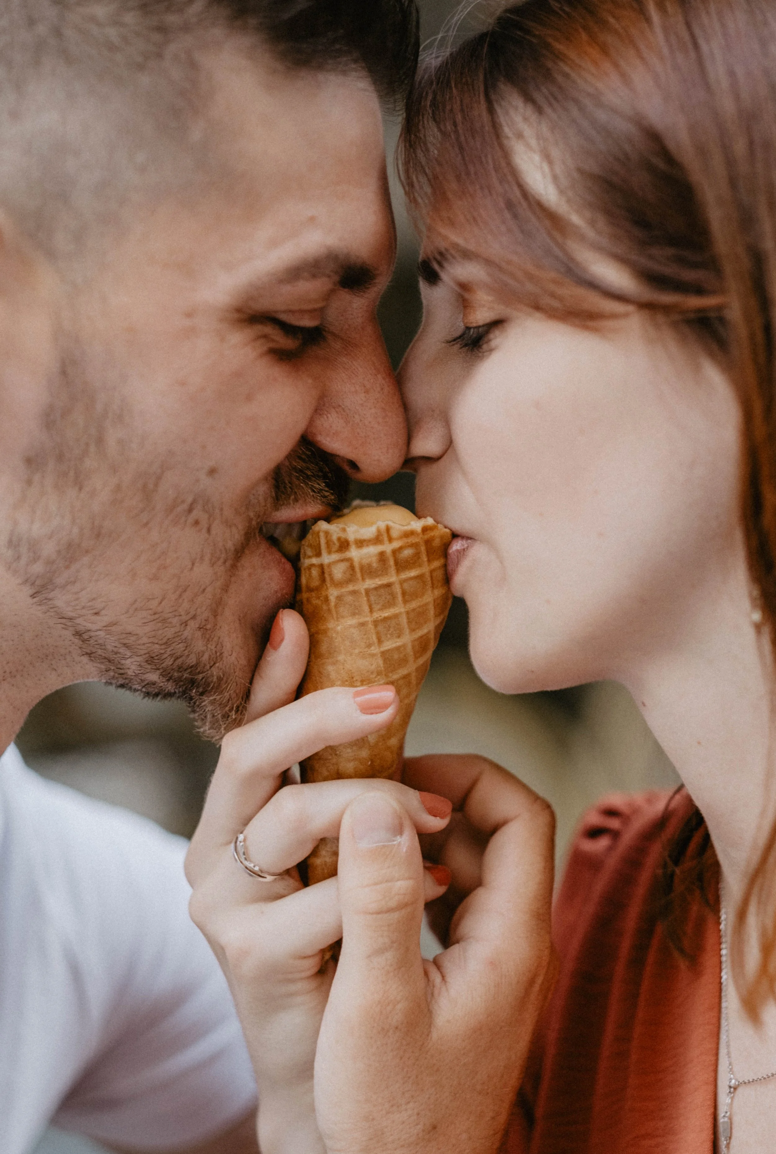 Un couple partageant une glace dans un close-up, leur visage est très proche, souriant doucement.