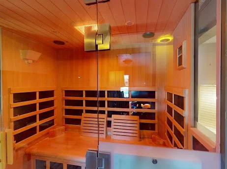 Inside a wooden sauna with a glass door, benches, and a window with a view.