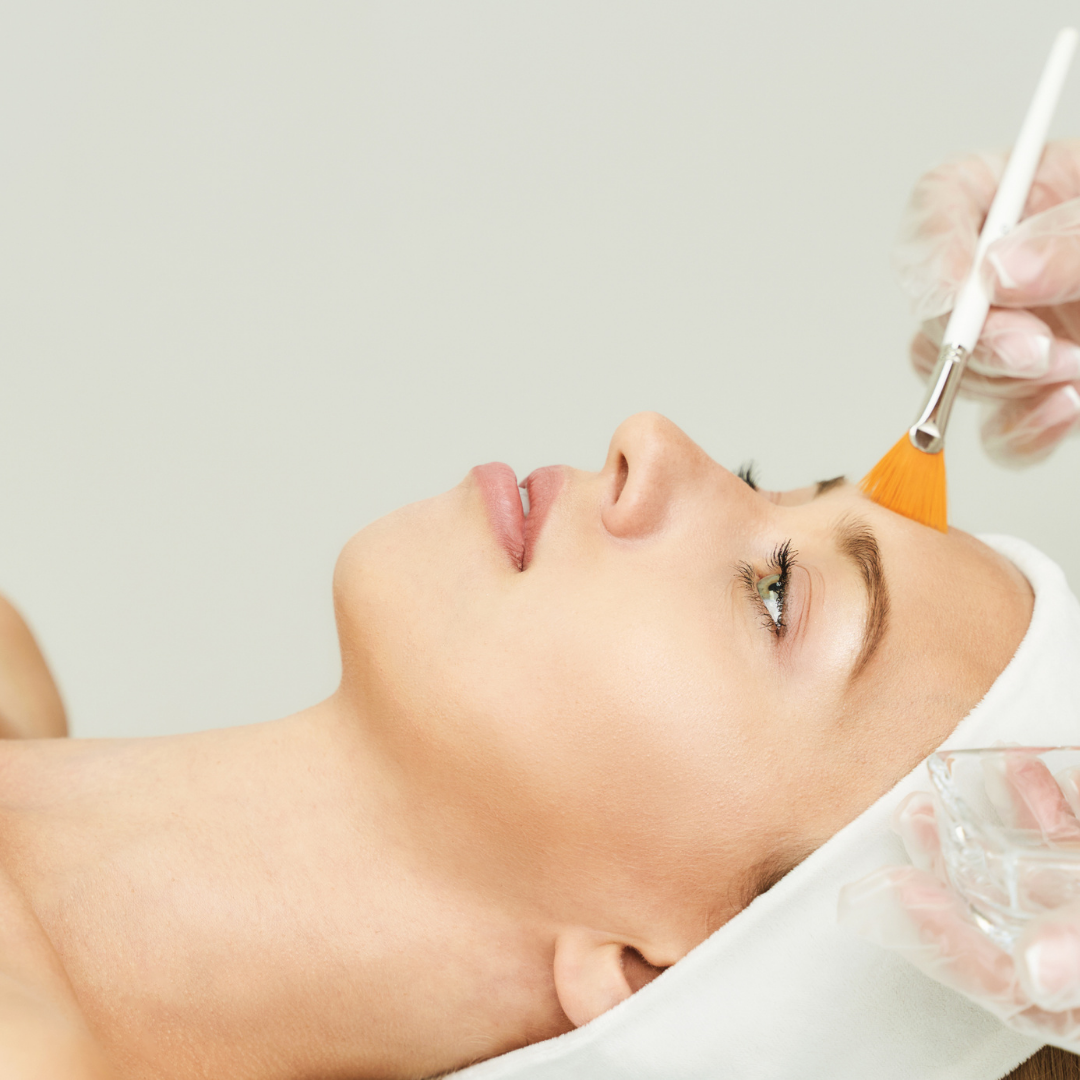 Woman getting a facial treatment with a brush on her forehead at a spa or skincare clinic.