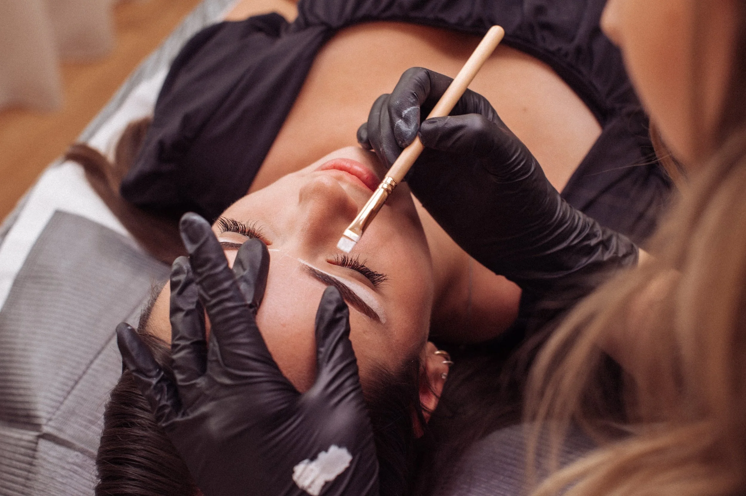 Beauty therapist creating the perfect brow shape in a beauty clinic for a woman