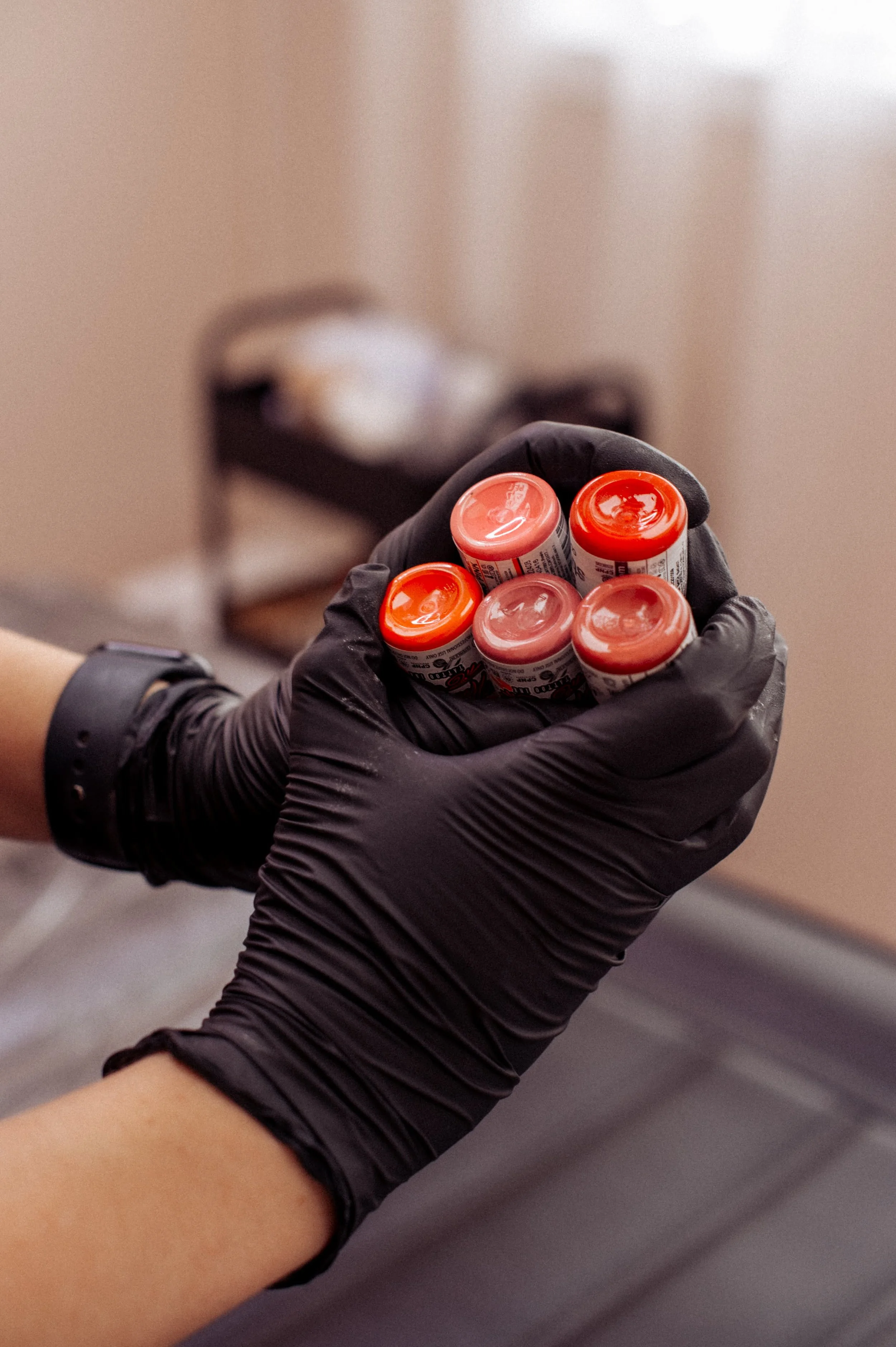 Cosmetic tattooist holding cosmetic lip tattoo colours in sterile gloves in a beauty salon