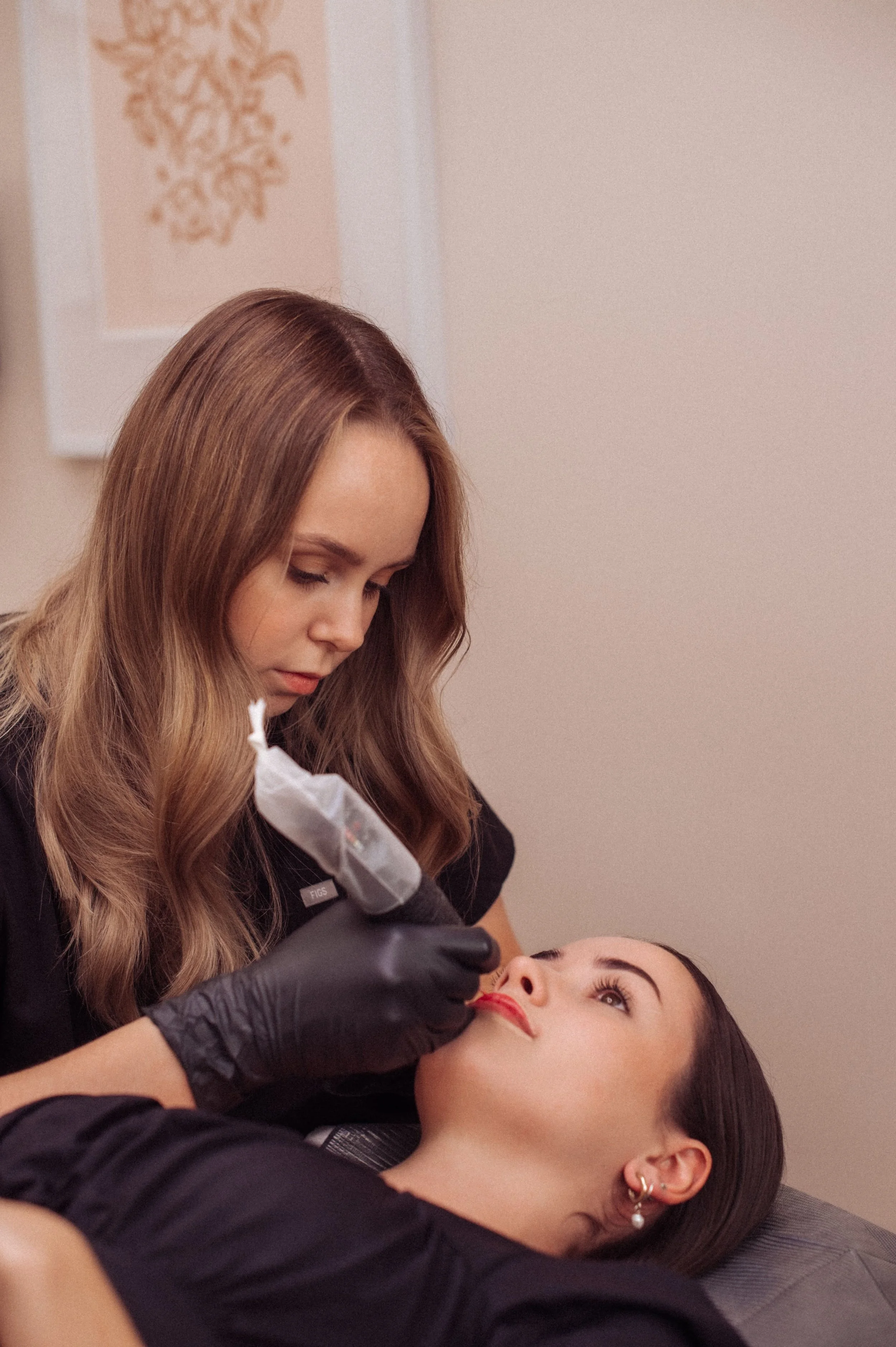 Cosmetic tattooist doing a cosmetic lip tattoo on a customer in a beauty salon