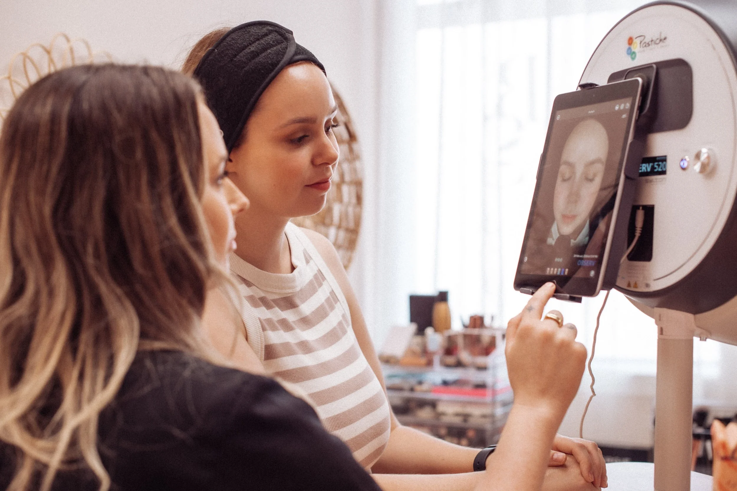 woman having a skin consult in a beauty clinic with a beauty therapist to see what her skin treatments and skincare products she needs. The beauty therapist is  showing the woman her skin pigmentation, skin redness and fine lines and wrinkles.