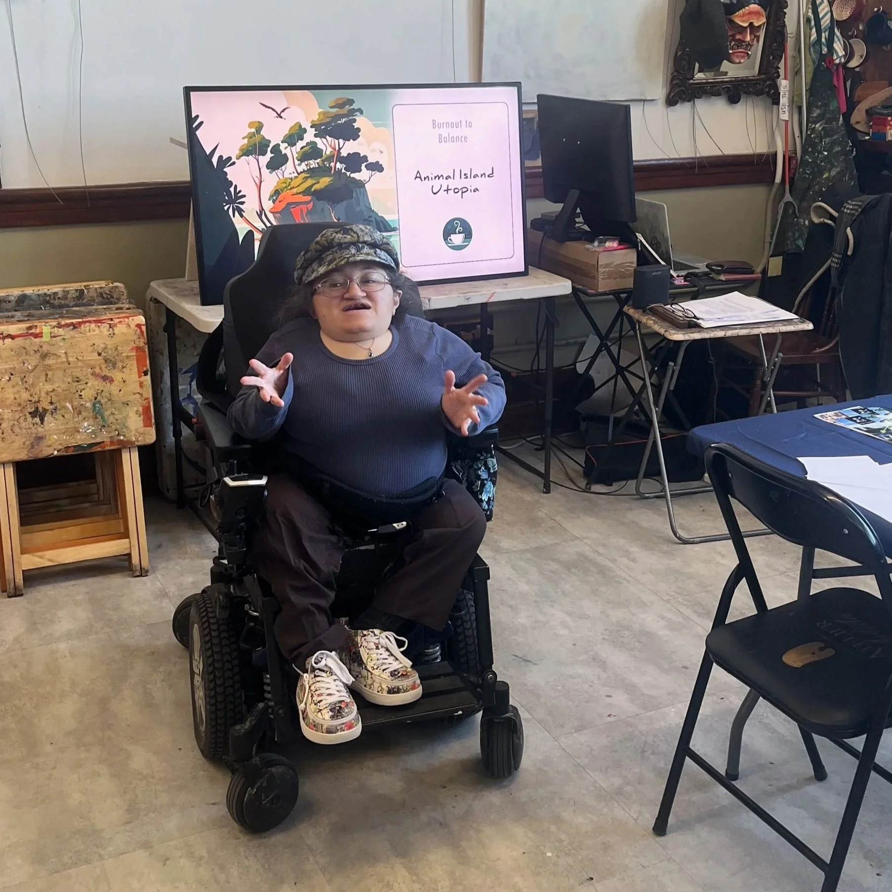 Athena sitting in her power wheelchair facilitating a workshop in an art studio setting.