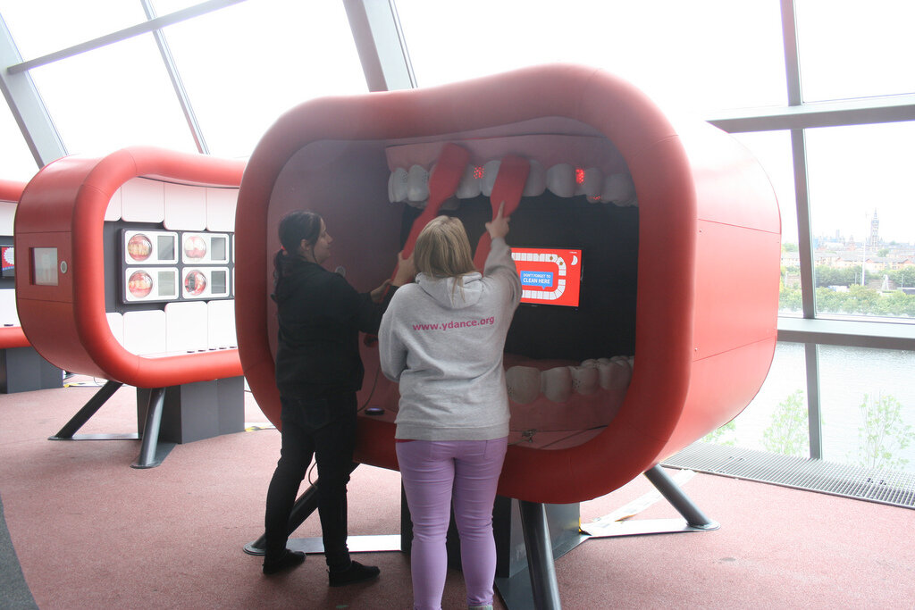 'Plaque Attack' Exhibit - from the travelling exhibition 'Keep Britain Smiling' which was made by KCA London for Colgate. Visitors have to brush the giant teeth and eliminate the plaque as it builds up (shown by glowing red LEDs). Sensors within the