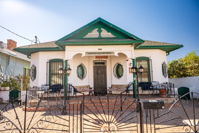 White house with green shutters and a wrought iron gate out front