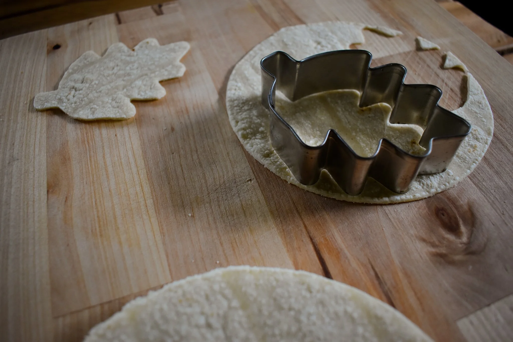 Leaf cookie cutter pressing out a shape in a tortilla