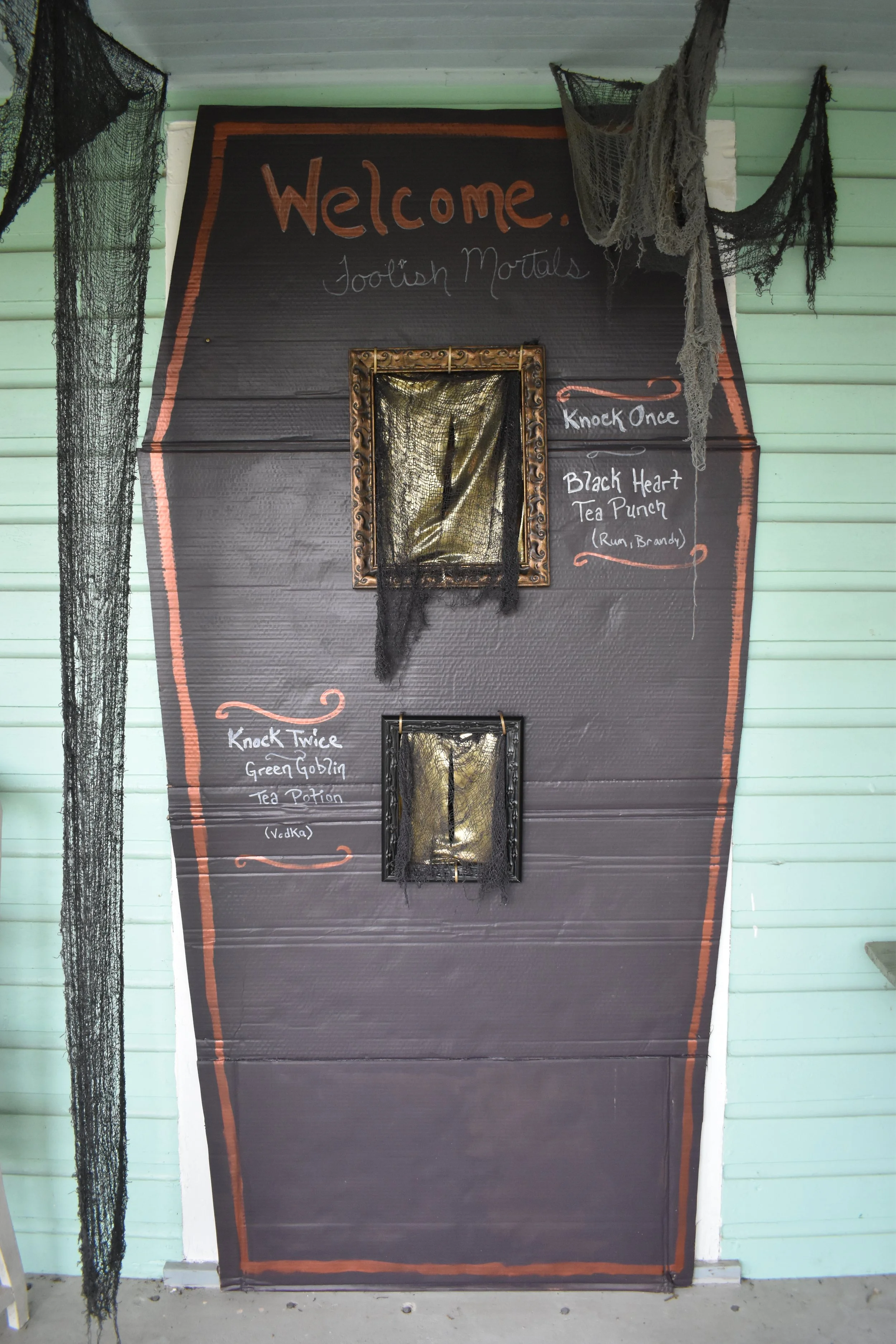 close-up photo of carboard coffin shape covering a doorway with holes cut and framed in the center