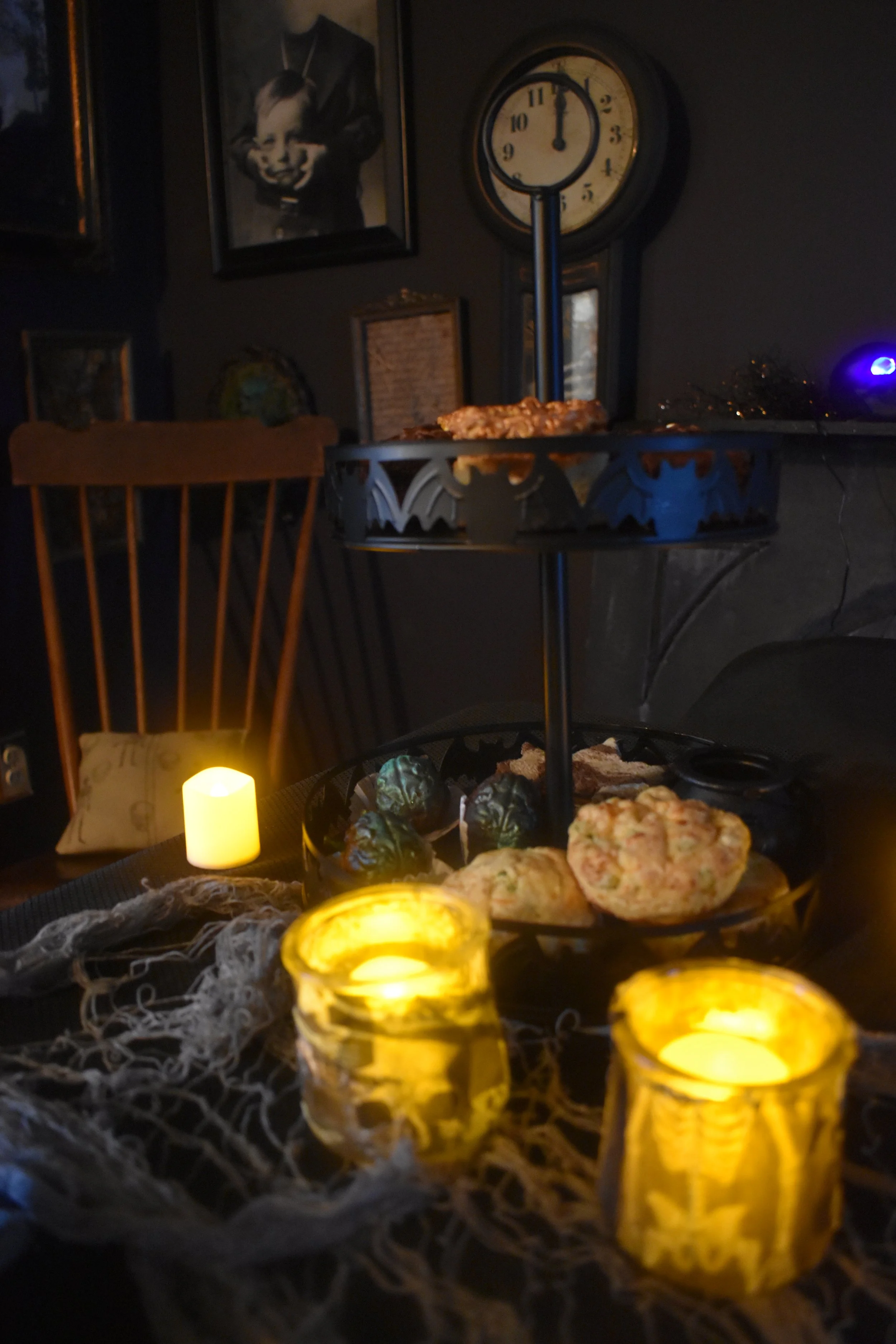 two-tiered tray with treats surrounded by halloween decorations and candles