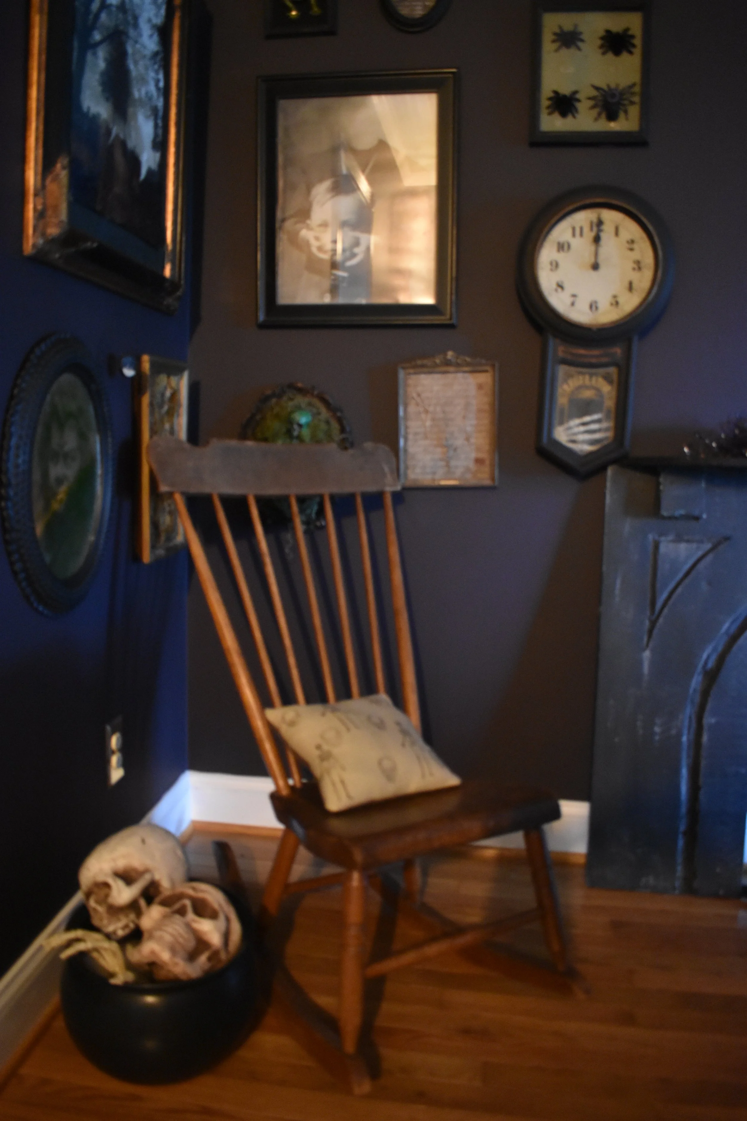 a gallery portrait wall with halloween portraits, a basket of skulls, and a rocking chair