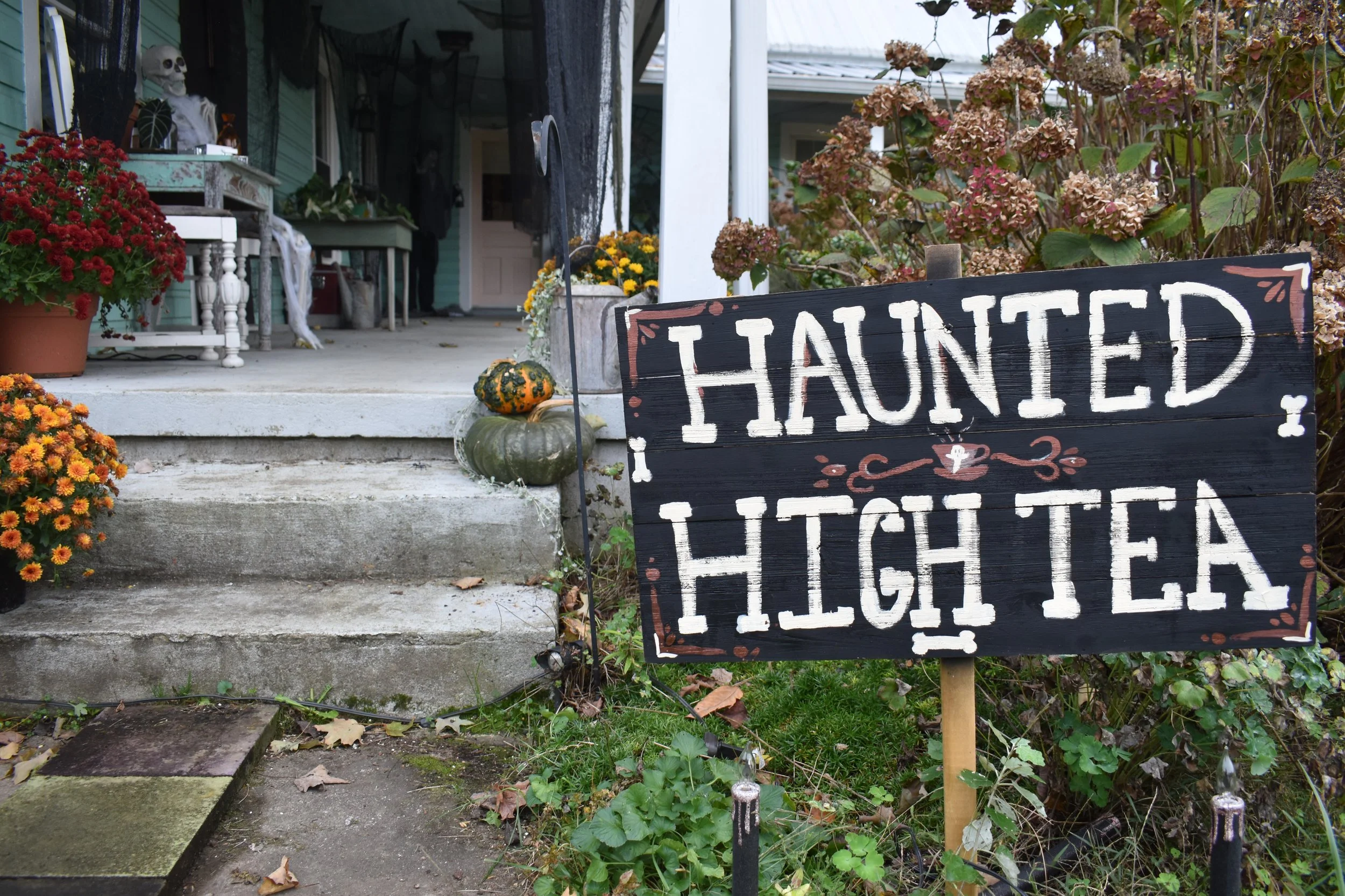 sign reading haunted high tea in front of a porch