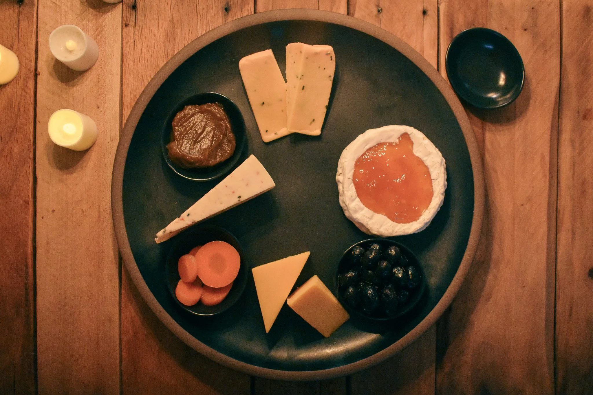 cheese wedges and tiny bowls on a black platter
