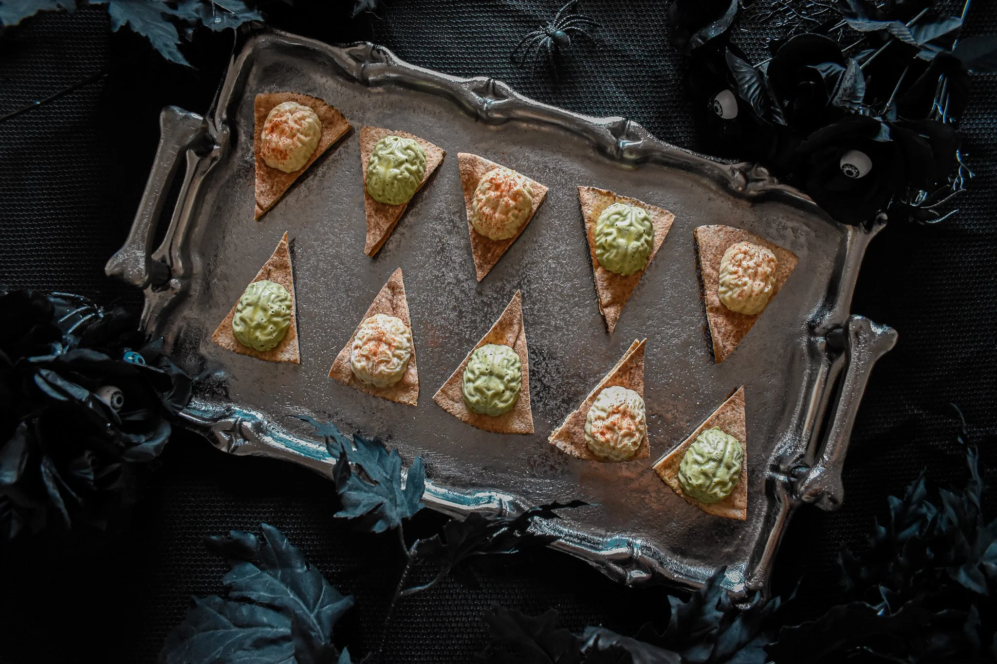 silver bone platter with pita triangles topped with hummus molded into the shape of brains