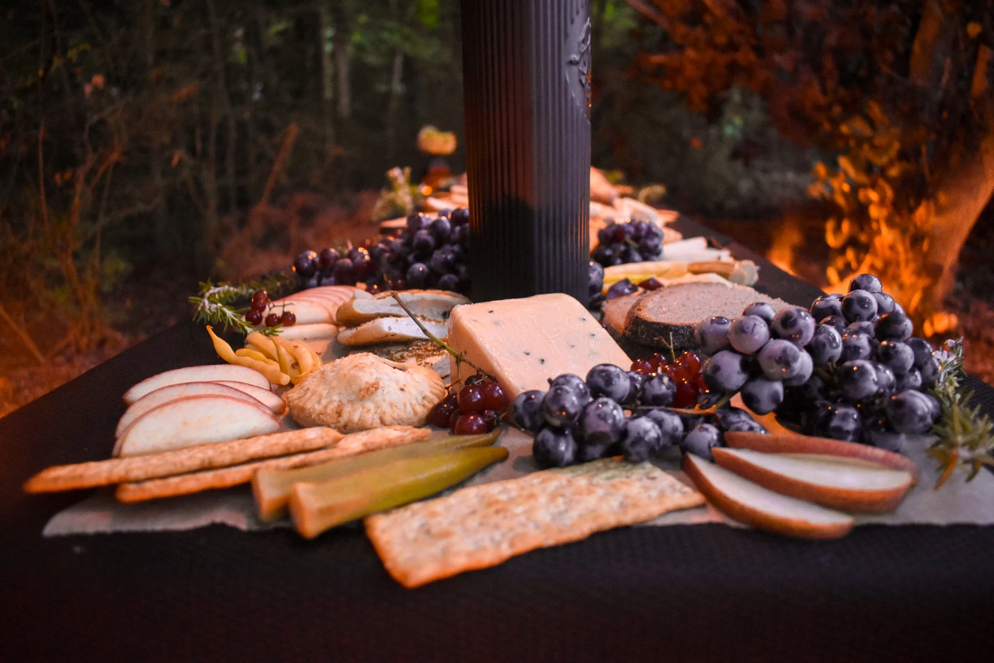 view of the table with cheese, crackers, pickles, and fruit