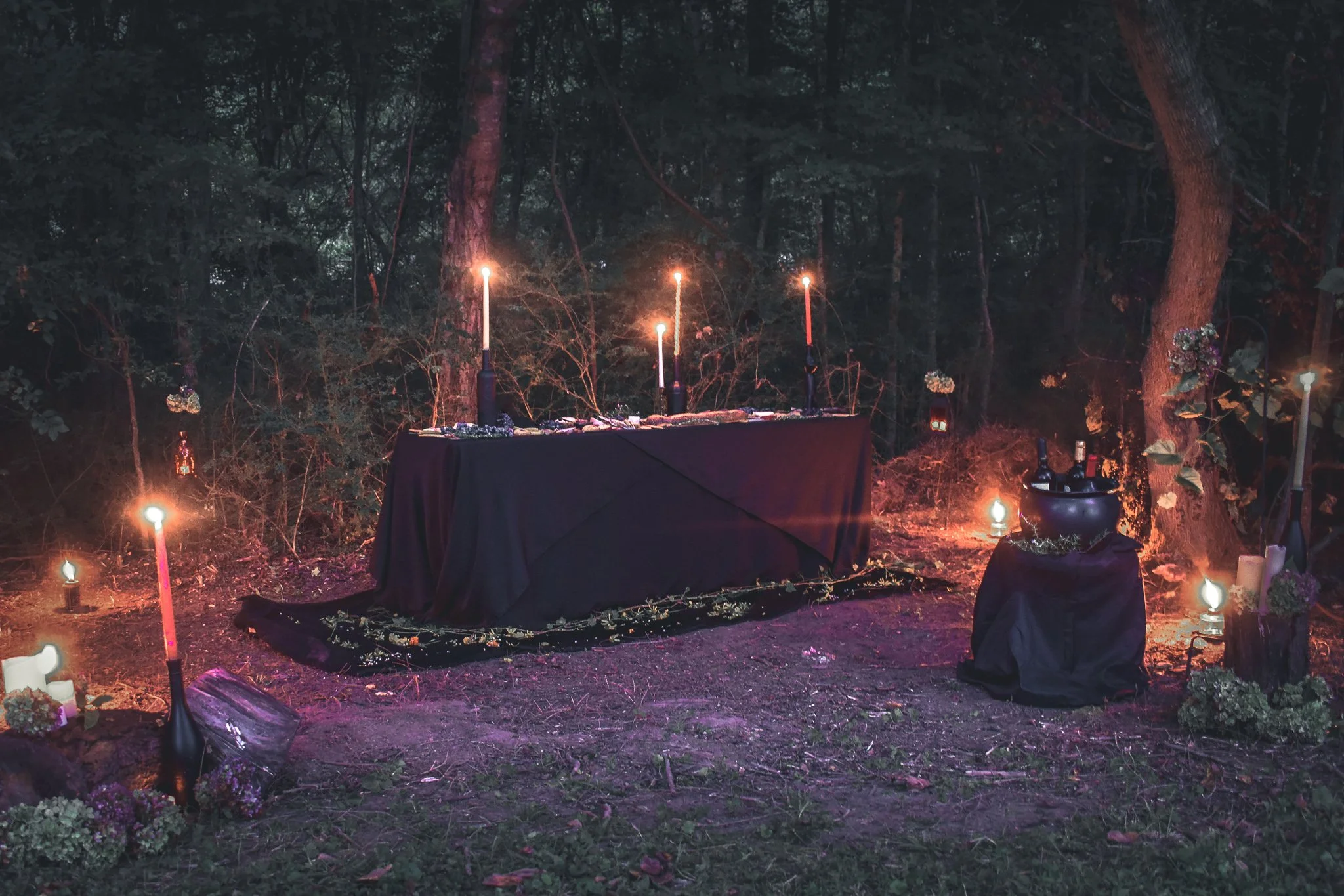 candlelit table in the woods surrounded by flower petals