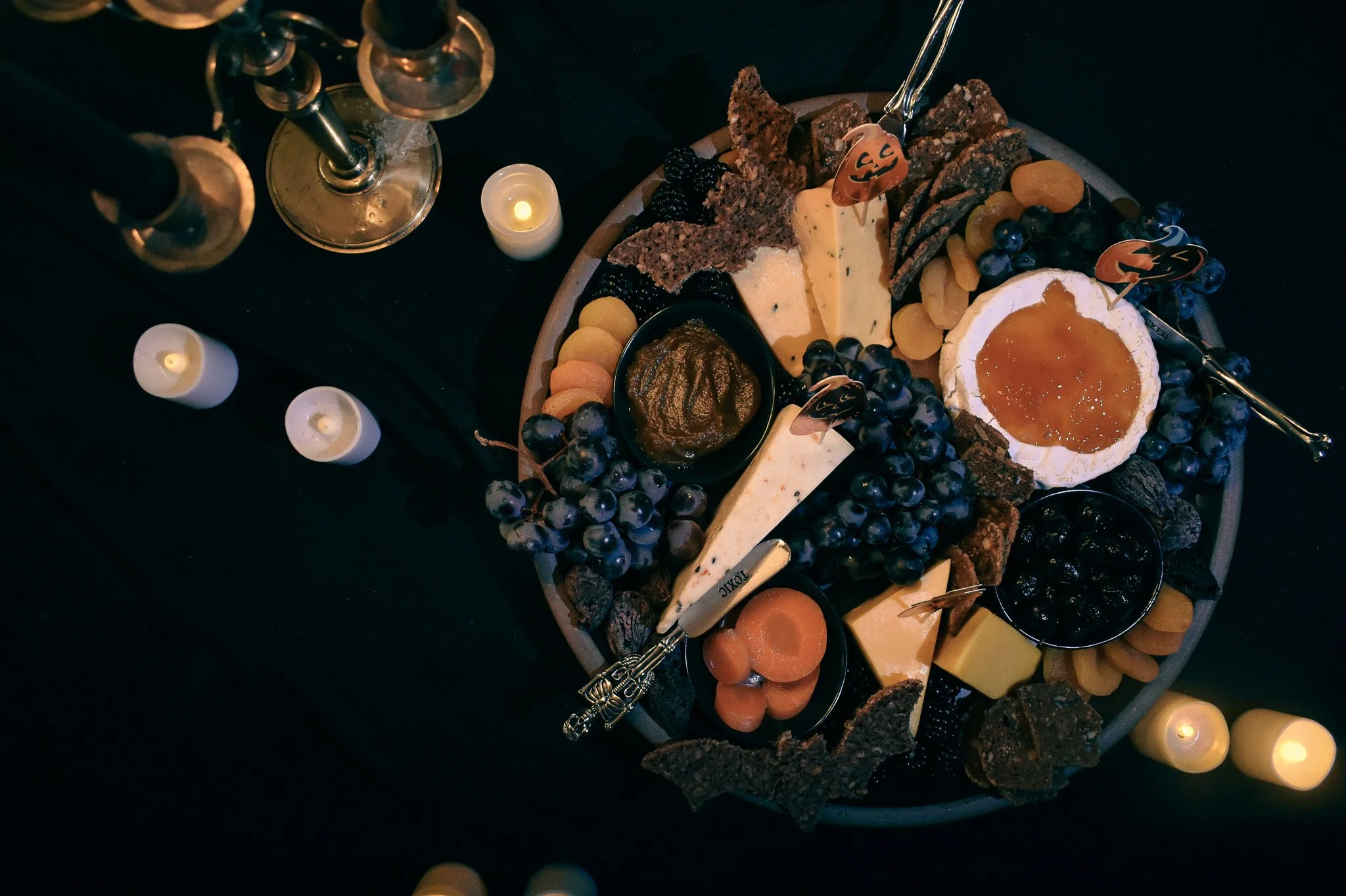 Cheese platter on a black background with candles around it