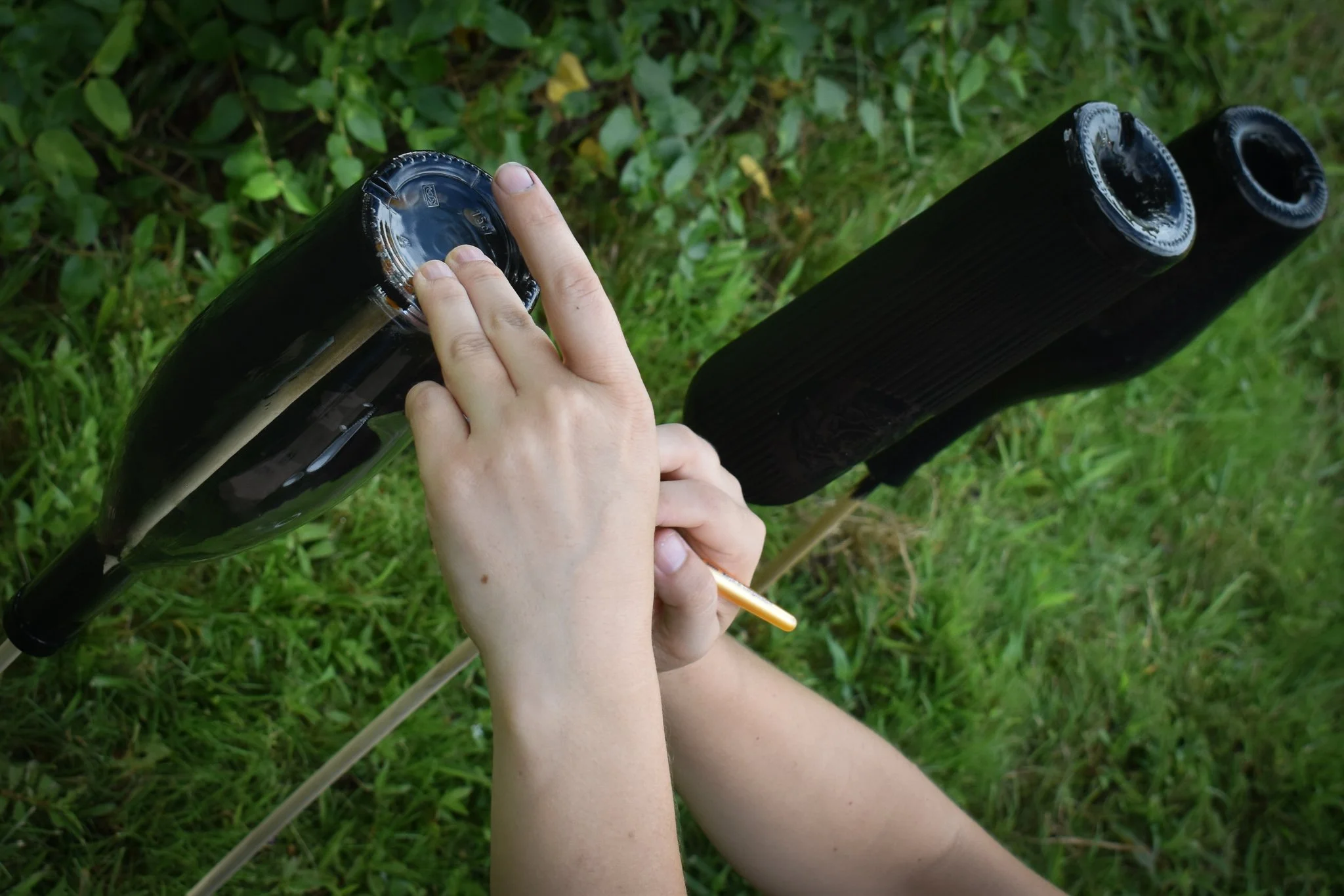 hands painting wine bottles black