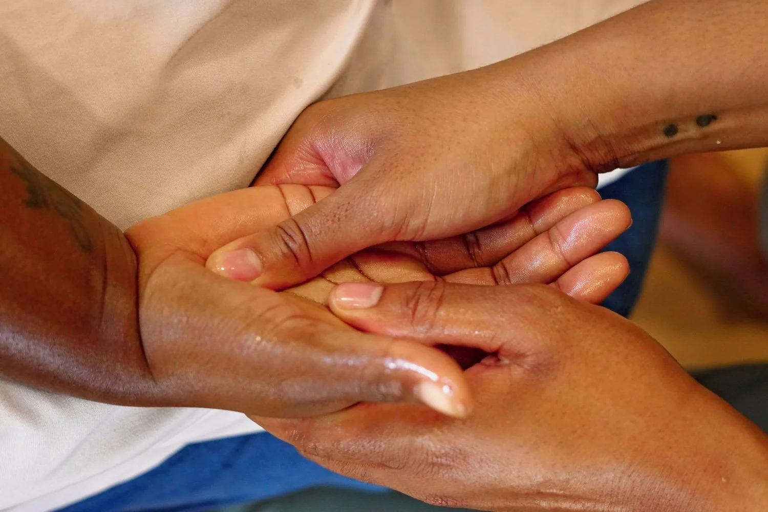 Two people holding hands, one person with dark skin and the other with slightly lighter skin.