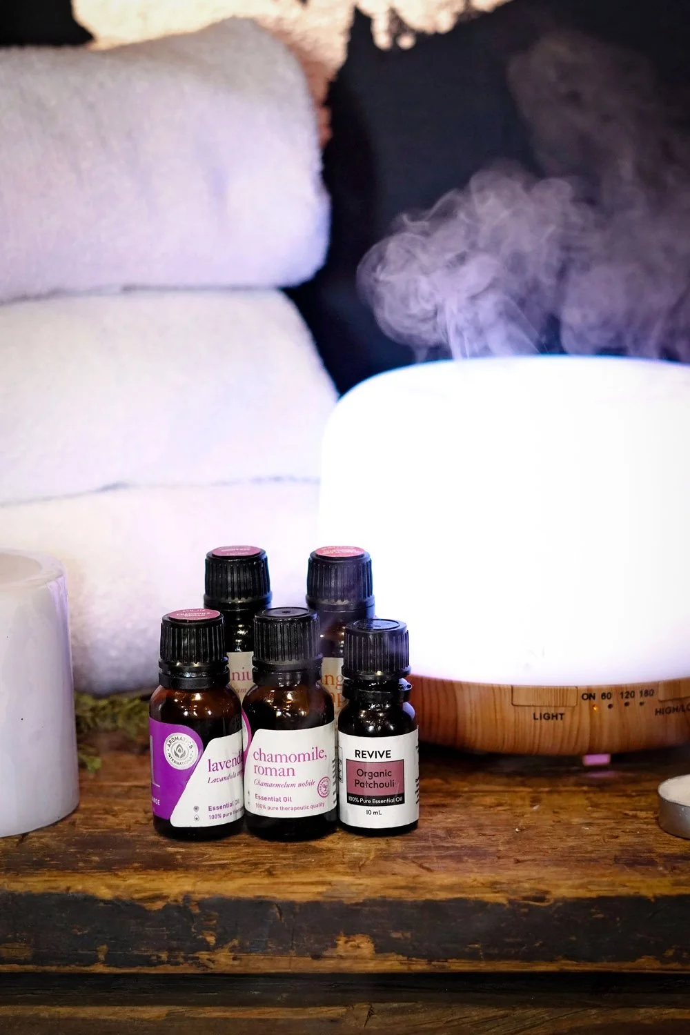 Aromatherapy diffuser, essential oils, and fresh towels arranged for a massage session.